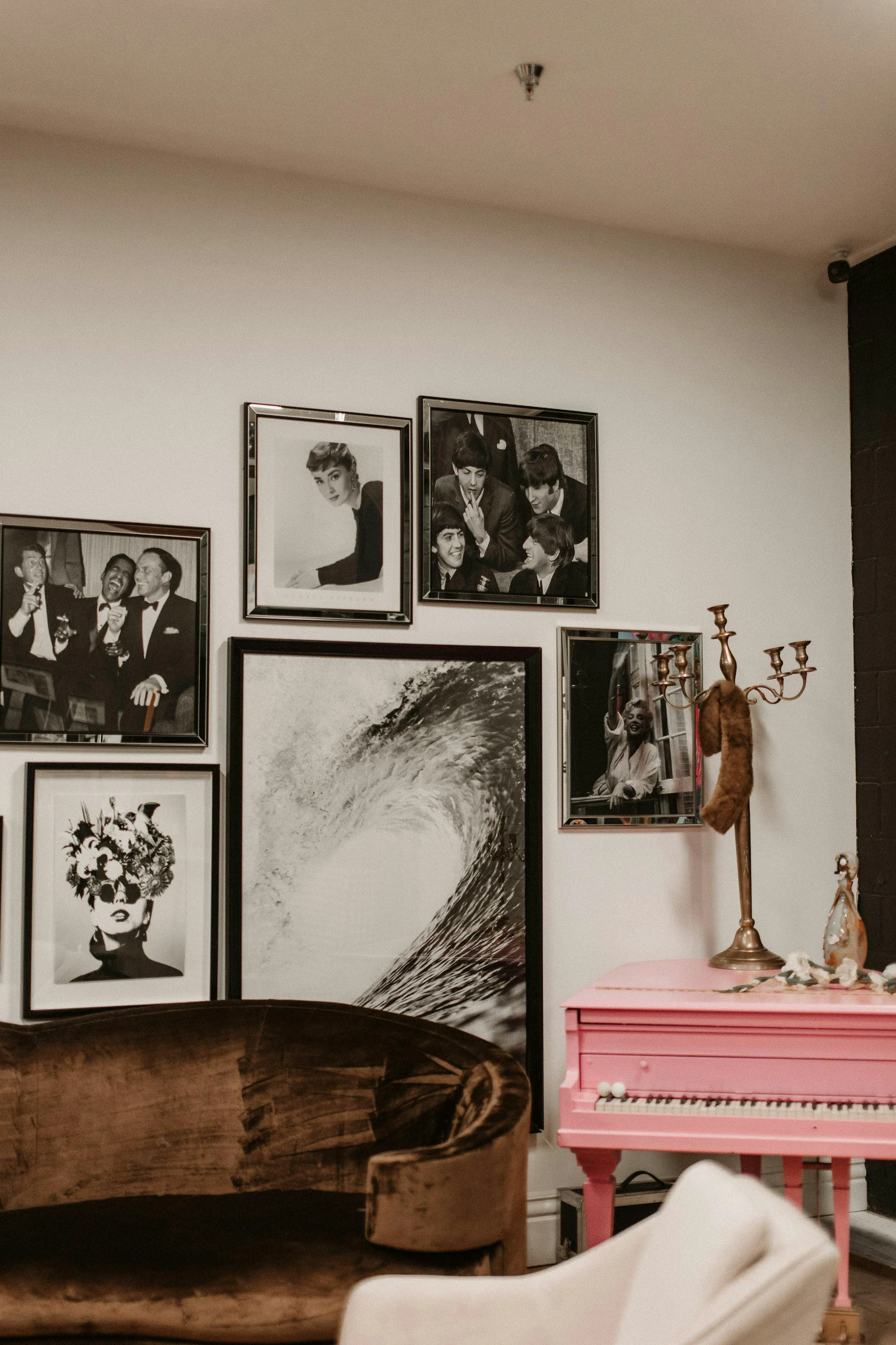 Eclectic living room featuring a vibrant pink piano, a vintage velvet chair, and a striking gallery wall with black and white portraits and artwork, an inspiring example of creative living room decor ideas for walls.