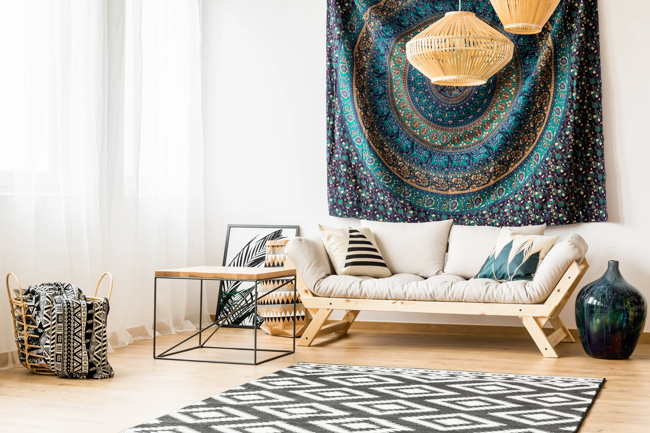 Bright and cozy living room with a wooden-framed sofa, geometric decor, and a vibrant tapestry wall art, offering stylish inspiration for living room decor ideas for walls.