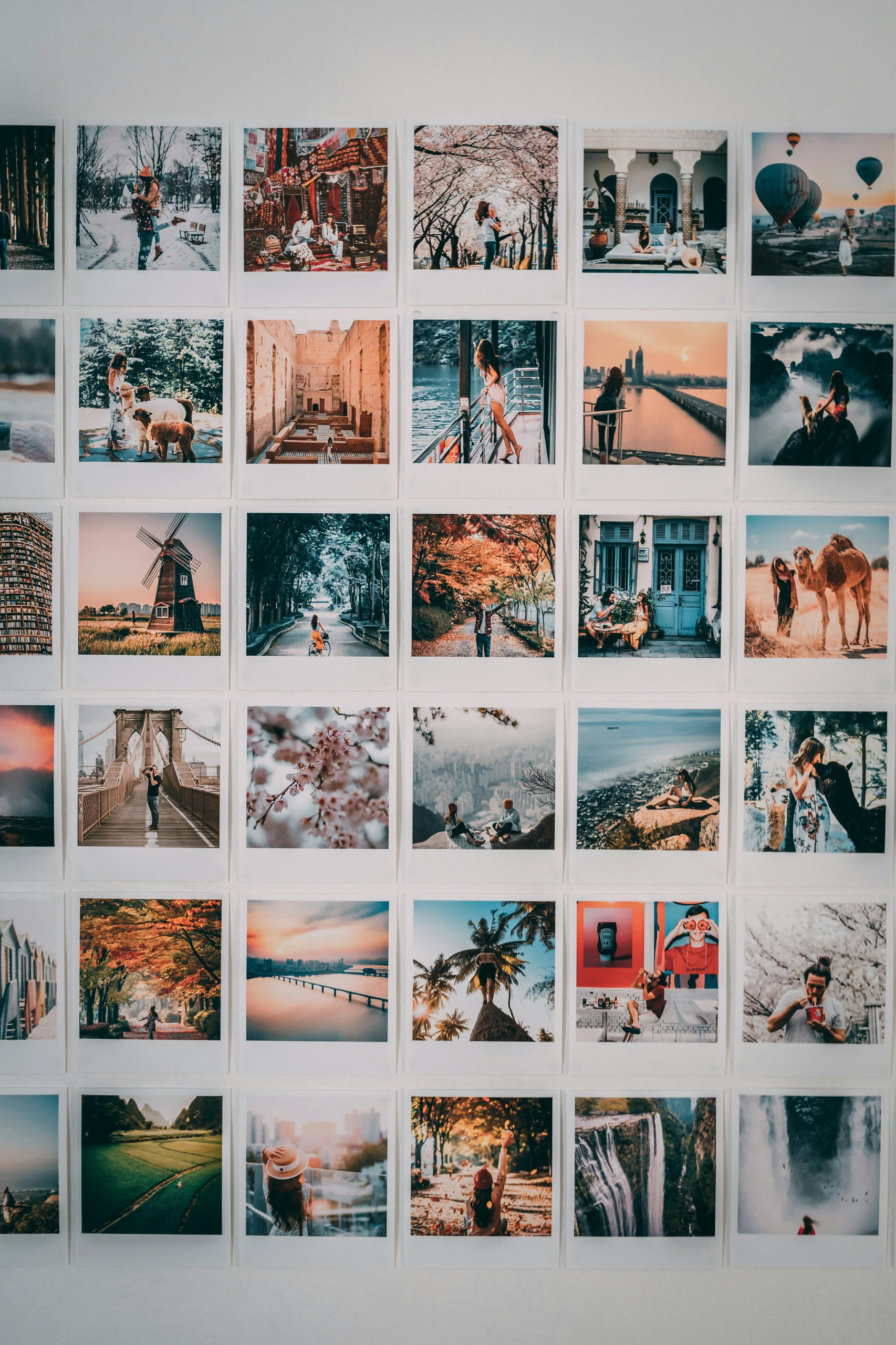 A creative photo wall featuring a grid of colorful snapshots from around the world, showcasing travel memories as part of inspiring living room decor ideas for walls.
