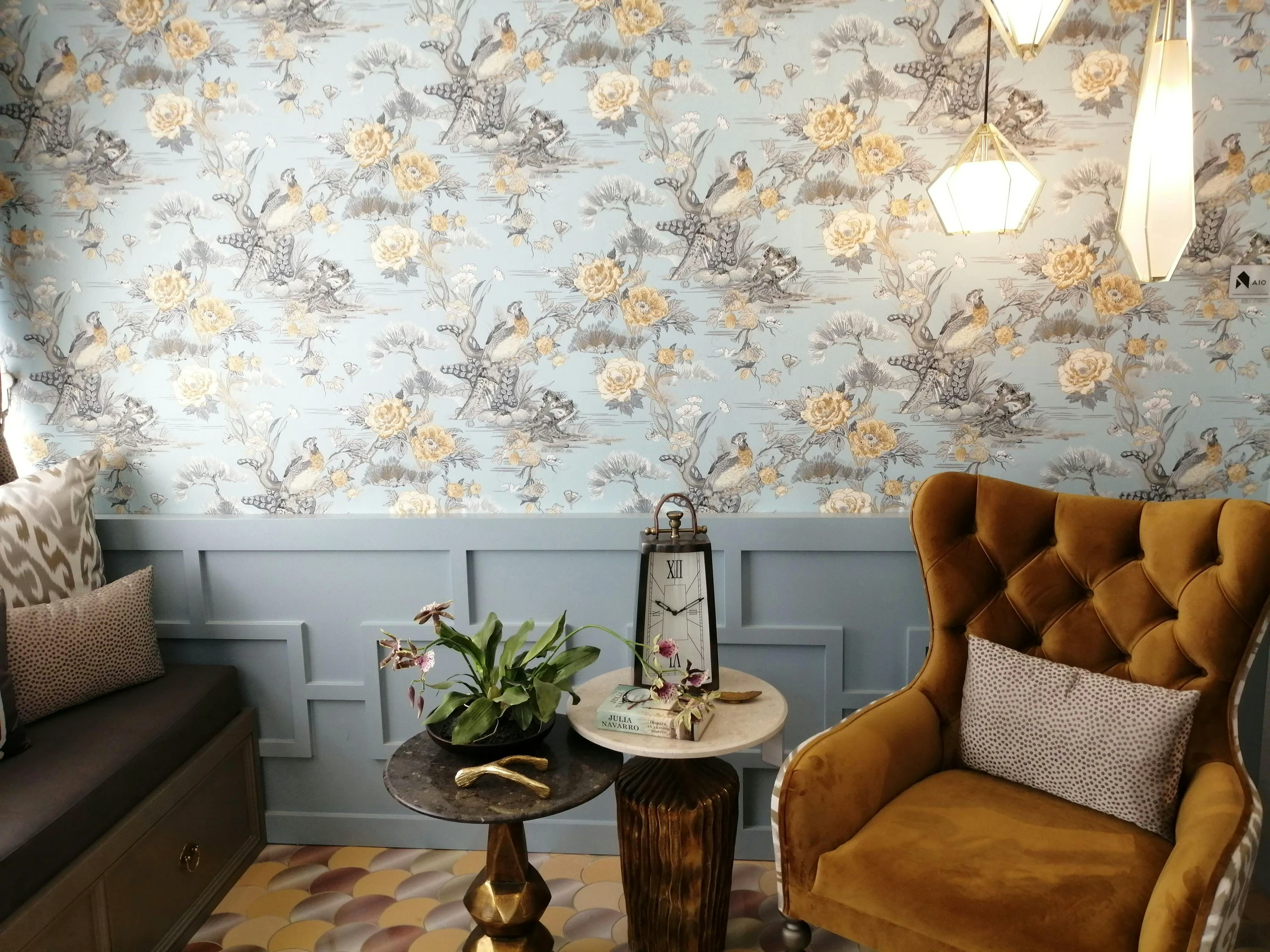 Cozy living room corner featuring a mustard velvet armchair, eclectic side tables, and striking patterned wallpaper with birds and florals. An elegant take on living room decor ideas for walls.