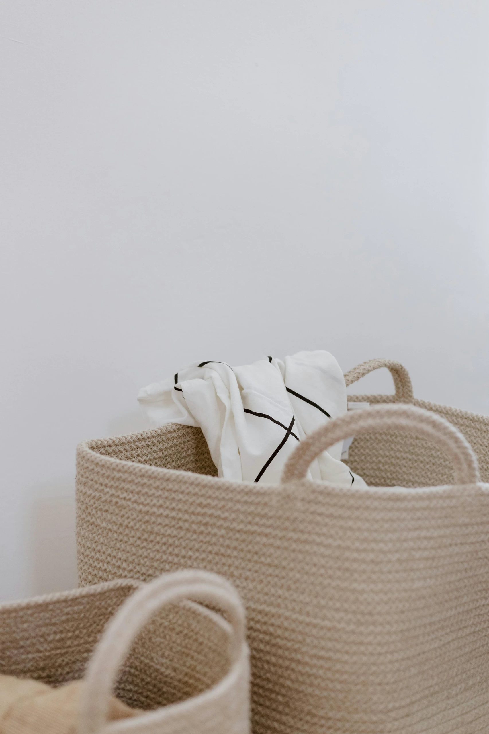 Close-up of neutral-toned woven baskets with a soft white cloth inside, showcasing minimalist living room farmhouse decor ideas that blend style and storage.