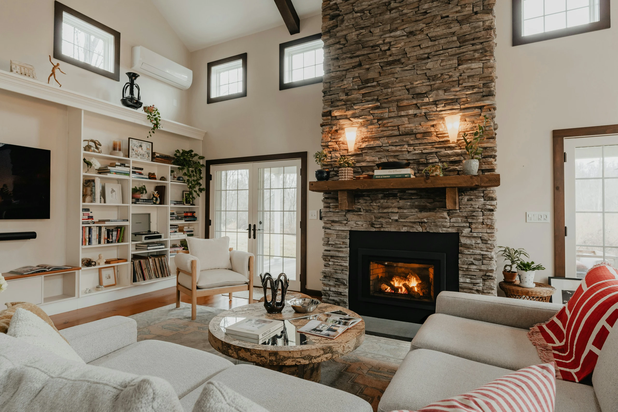 Cozy living room showcasing living room farmhouse decor ideas with a stunning stone fireplace, built-in bookshelves, neutral-toned furniture, and rustic wood accents for a warm, inviting atmosphere.
