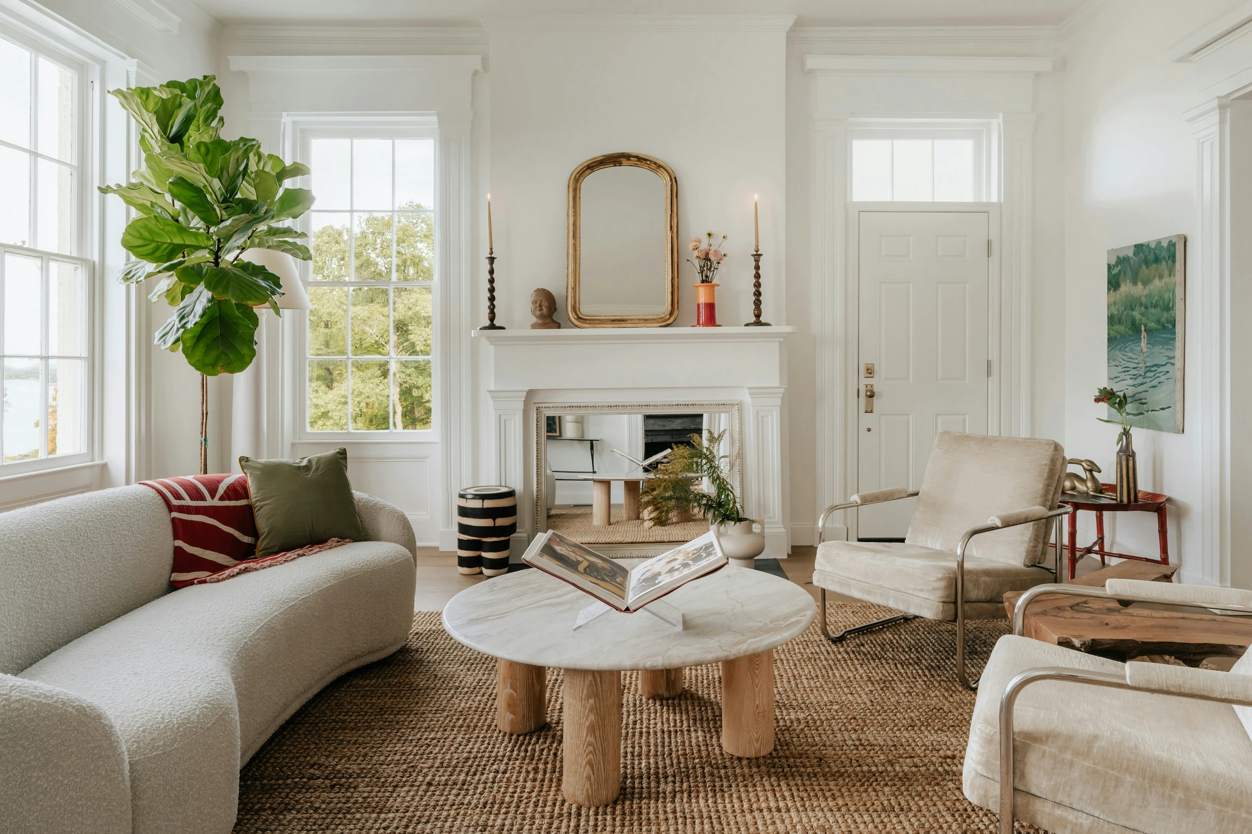 Elegant living room featuring living room farmhouse decor ideas with soft neutral colors, including a plush curved sofa, earthy-toned jute rug, natural wood accents, and a classic white fireplace for a cozy yet refined atmosphere.