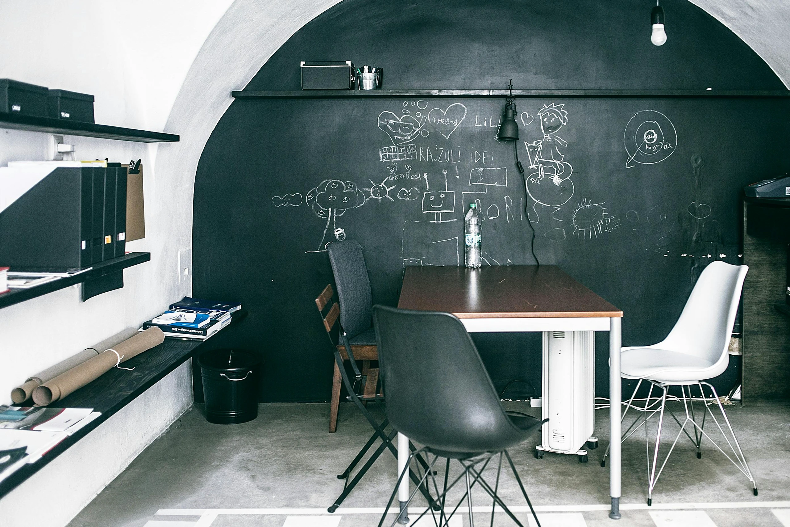 Modern space with a playful chalkboard wall covered in doodles and sketches, paired with a minimalist table and mixed chairs. An inspiring take on living room decor ideas for walls.