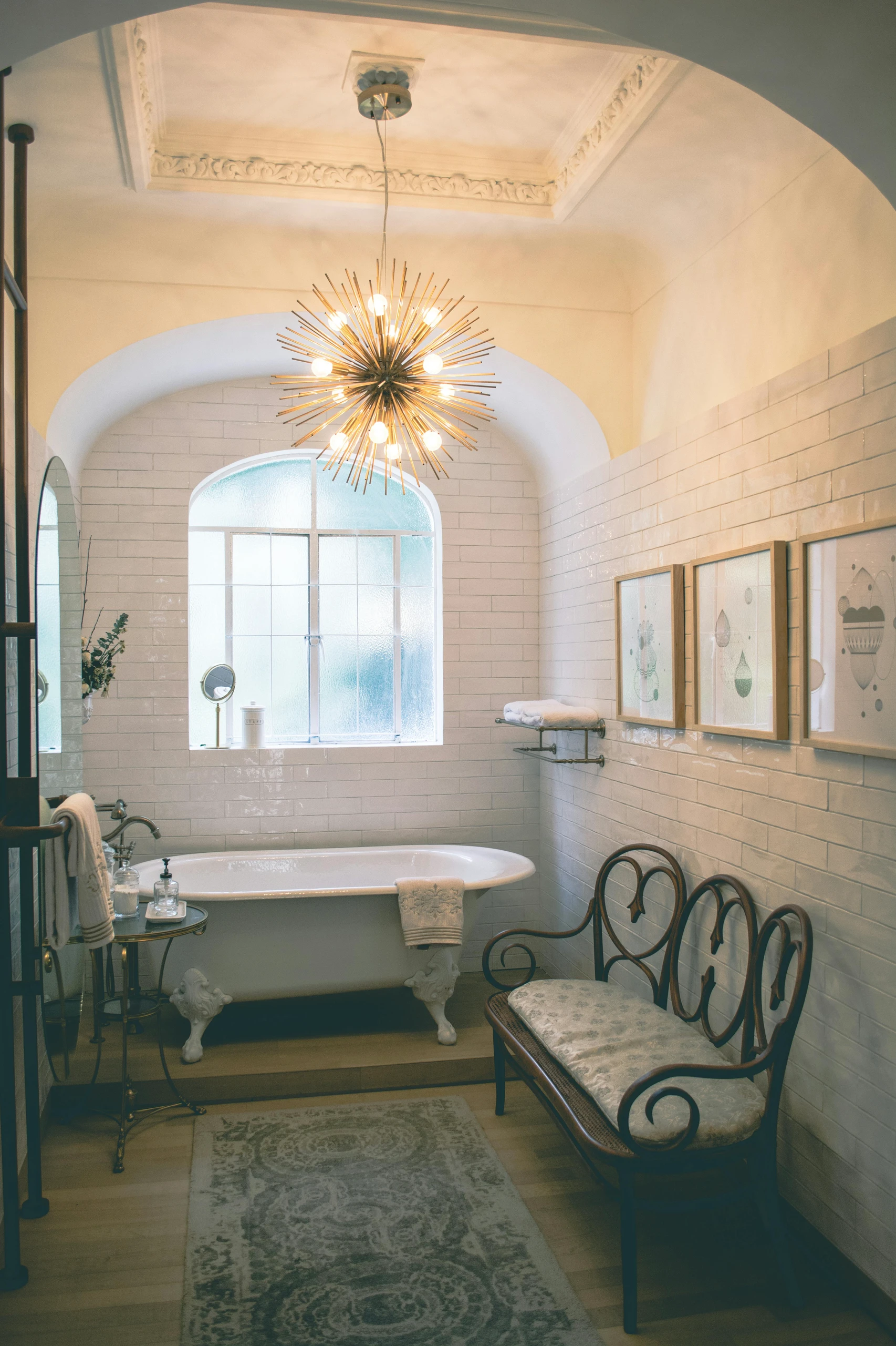 Elegant small bathroom featuring a clawfoot tub and statement chandelier, showcasing how to utilize the space in the corners with a side table and towel rack. Perfect for creative small bathroom ideas.