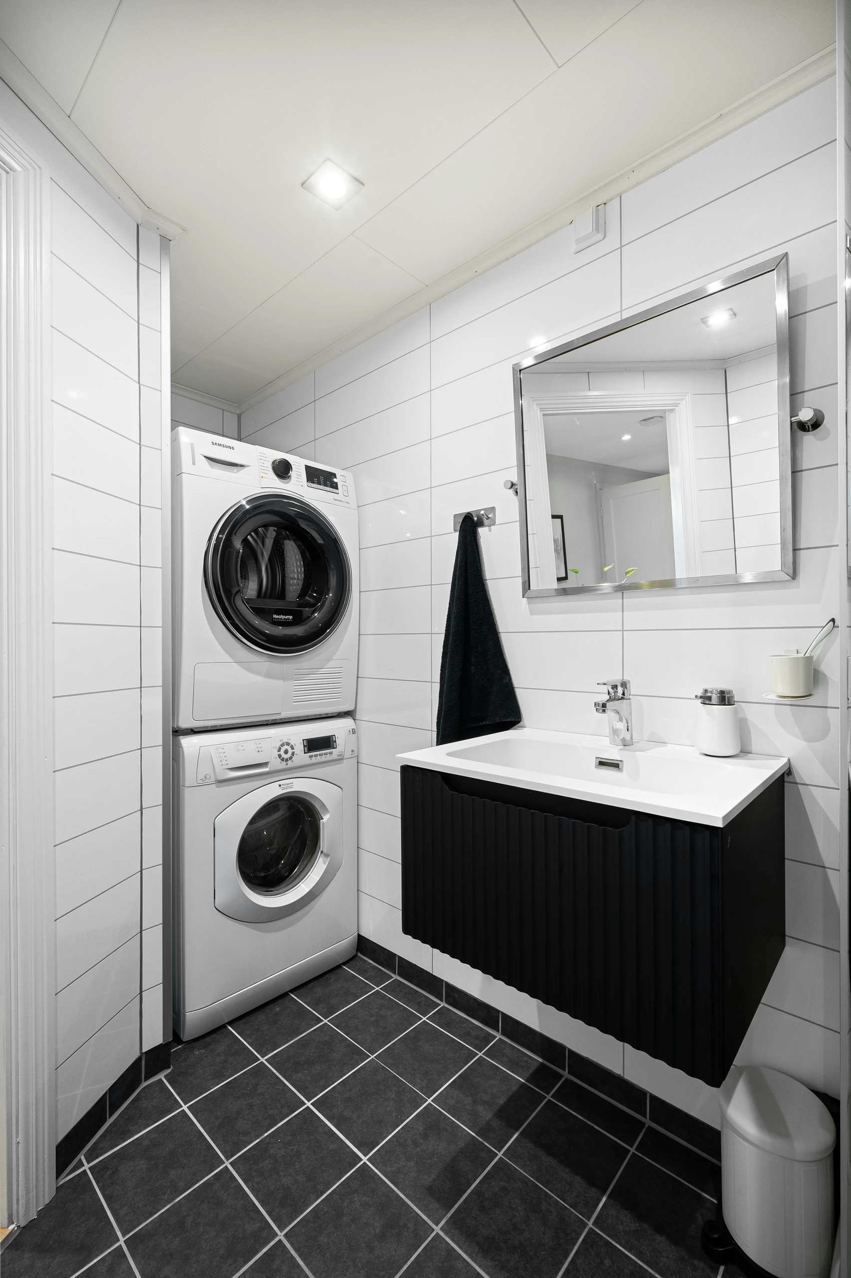 A modern and functional example of small bathroom ideas on a budget, featuring smart space-saving laundry integration with a stacked washer and dryer set tucked neatly into a corner. The minimalist design combines efficiency and style, maximizing utility without sacrificing aesthetics.