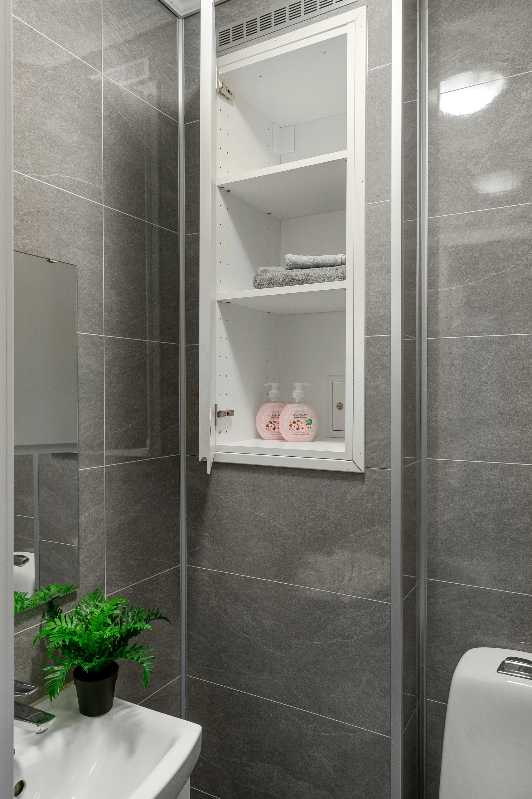 A sleek, space-efficient bathroom showcasing small bathroom ideas on a budget, featuring a clever recessed cabinet that reveals secret storage treasures behind a mirrored door. Ideal for keeping toiletries and towels neatly organized while maintaining a minimalist and modern aesthetic.