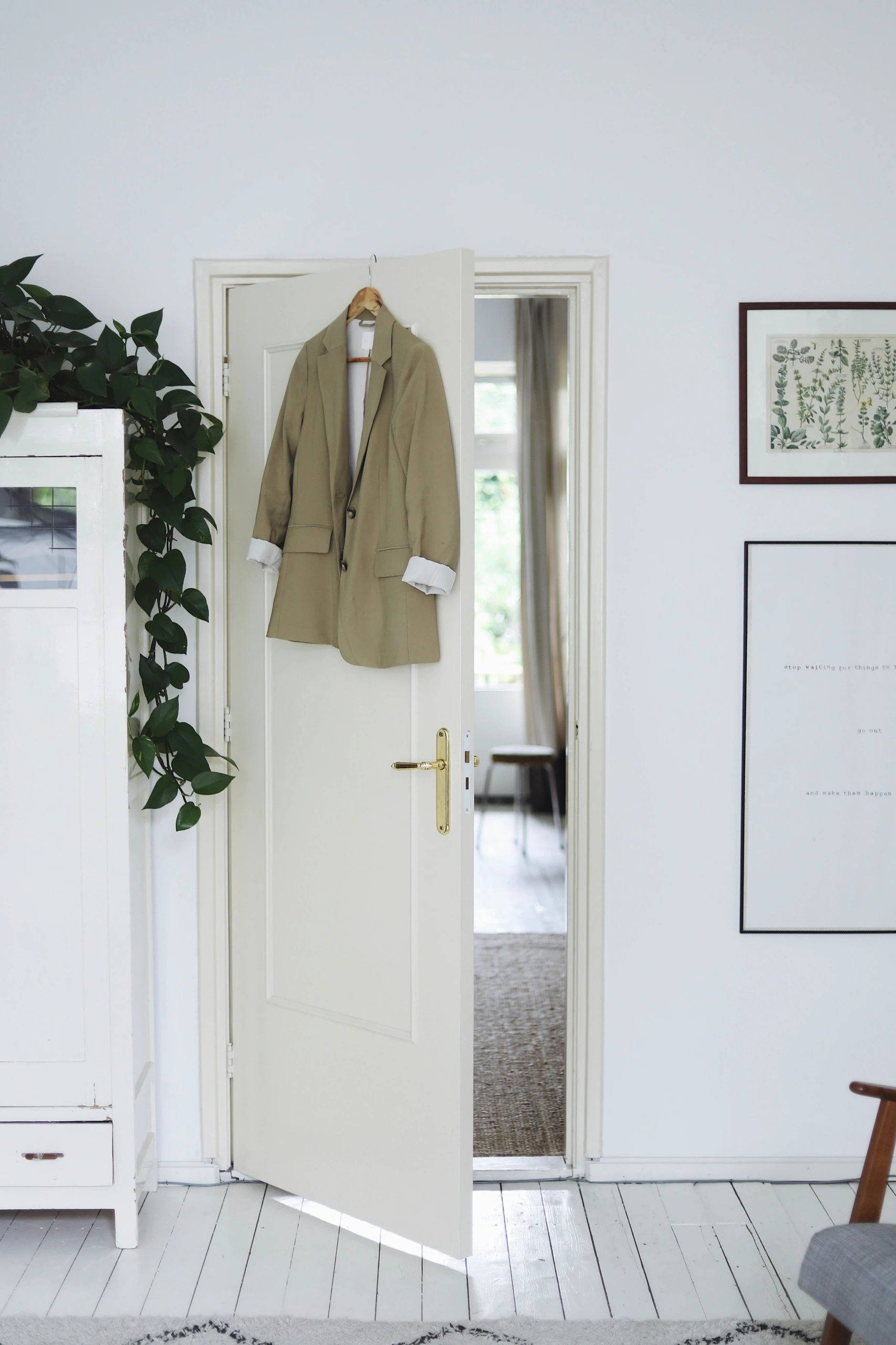 Minimalist white bedroom showcasing small bedroom ideas with storage, featuring an over-the-door-organizer in the form of a hanger holding a beige blazer to maximize vertical space efficiently.