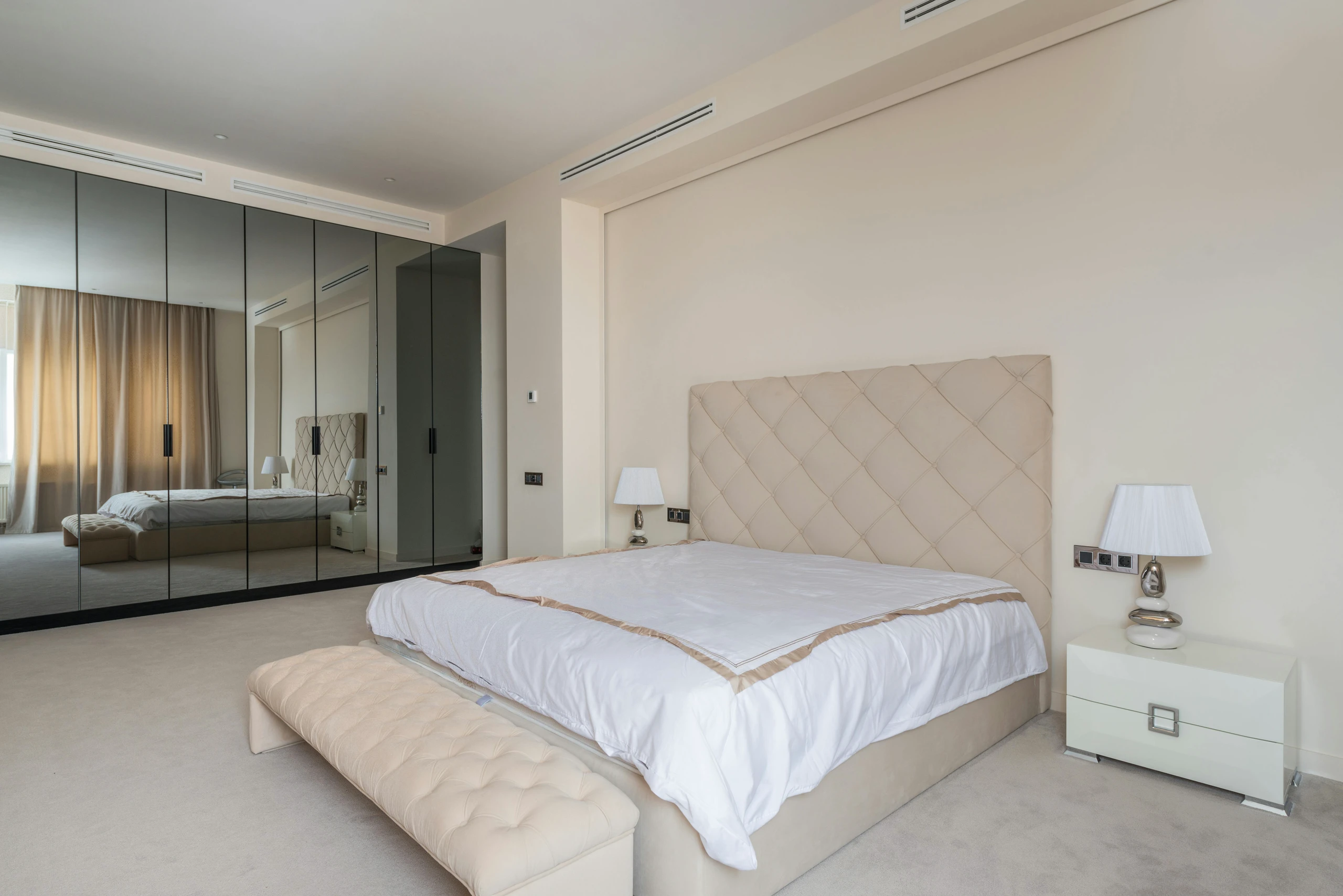 Elegant minimalist bedroom featuring a large mirror cabinet that visually expands the space, offering a smart solution for small bedroom ideas with storage.