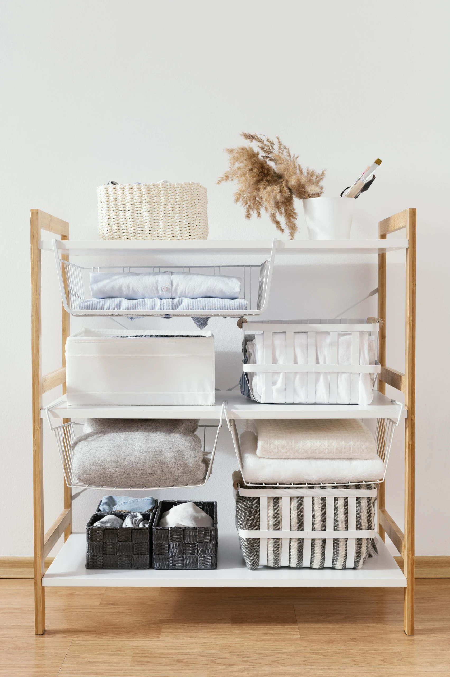 Open shelving unit featuring baskets, bins, and folded linens, exemplifying small bedroom ideas with storage through a neatly organized bedside setup that maximizes vertical space while maintaining a clean, minimalist look.