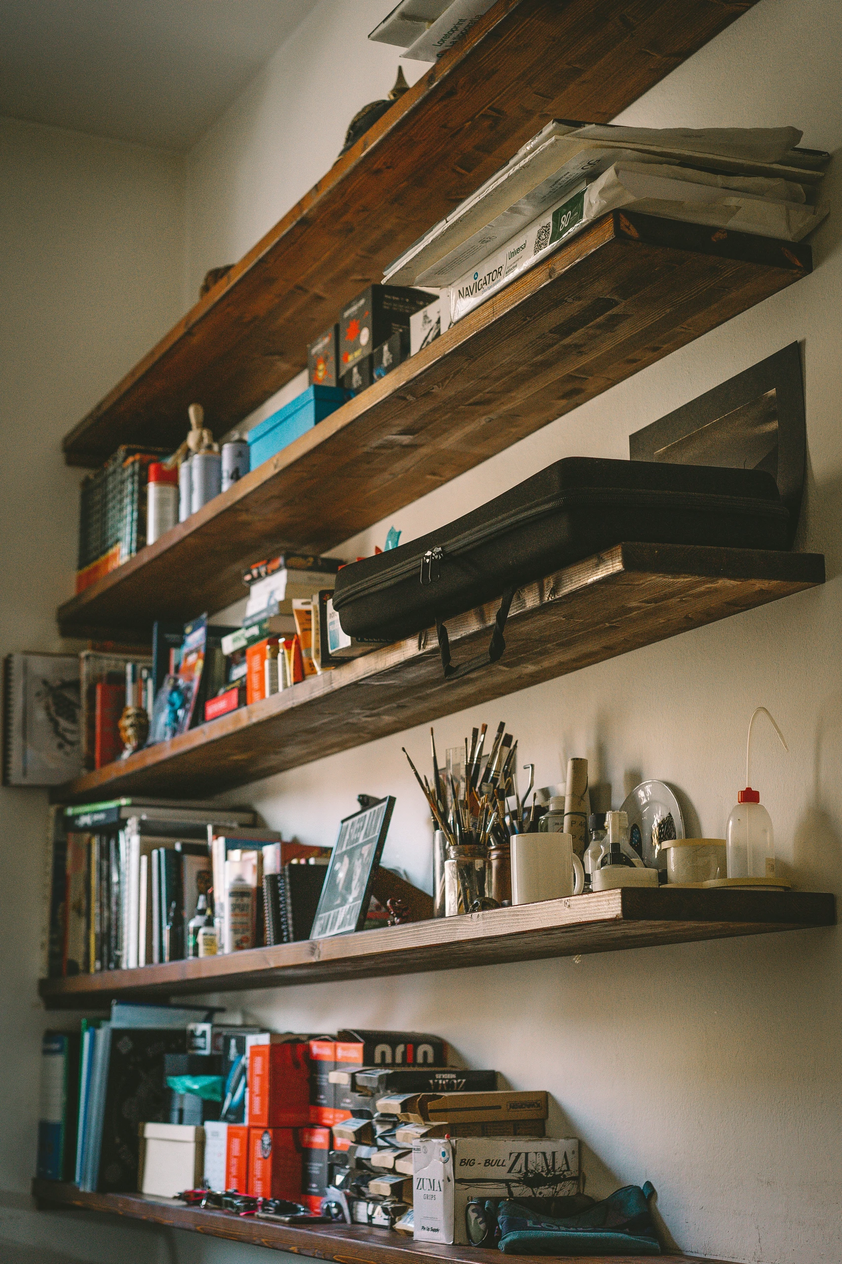 Large vertical wooden shelves filled with books, art supplies, and storage boxes in a small bedroom - a smart example of small bedroom ideas with storage using large vertical shelves for maximum organization.