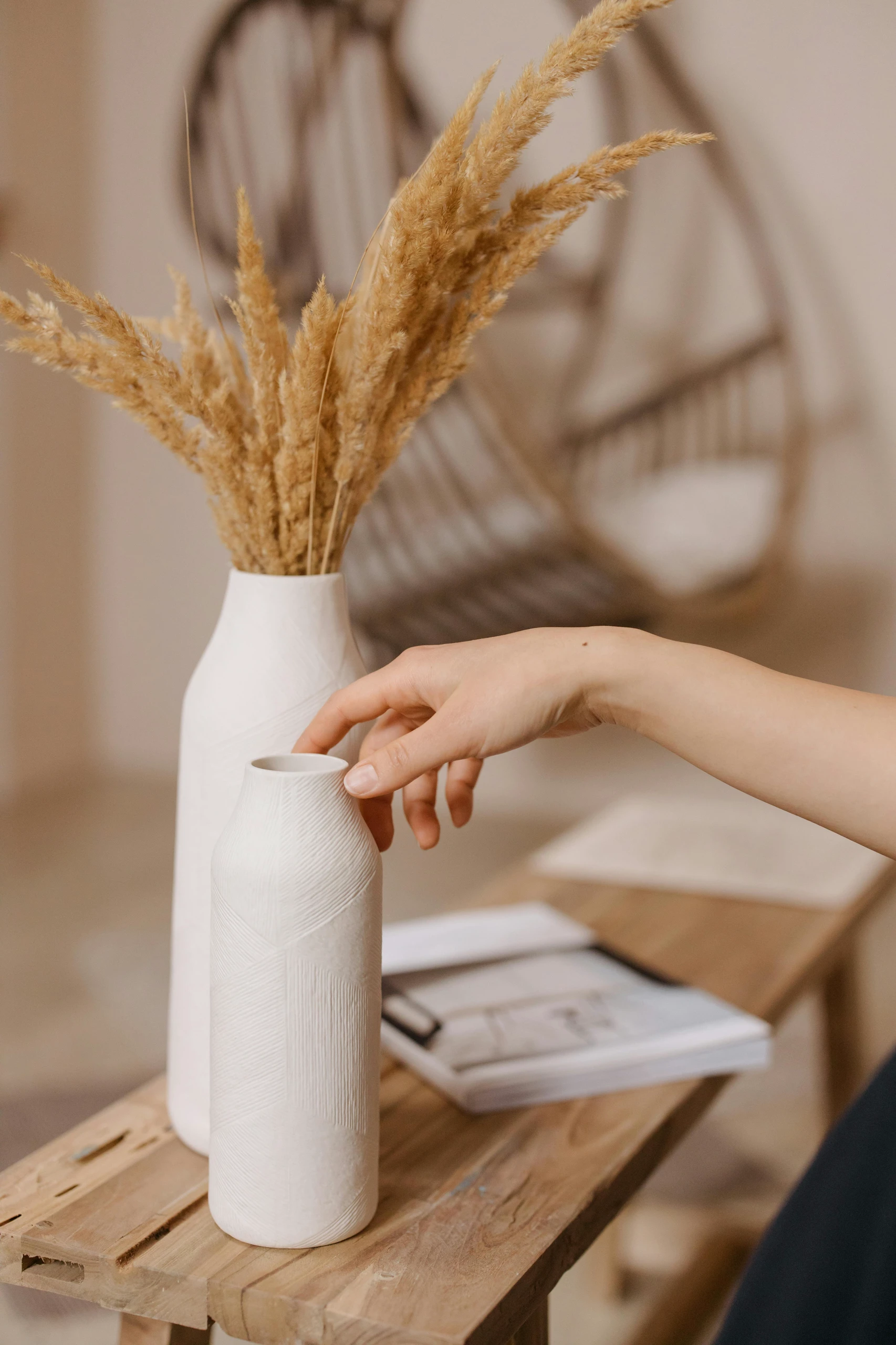 Stylish dining table centerpiece ideas featuring a minimalist white vase with pampas grass, complemented by a second decorative vase and neutral-toned decor for a cozy, natural look.