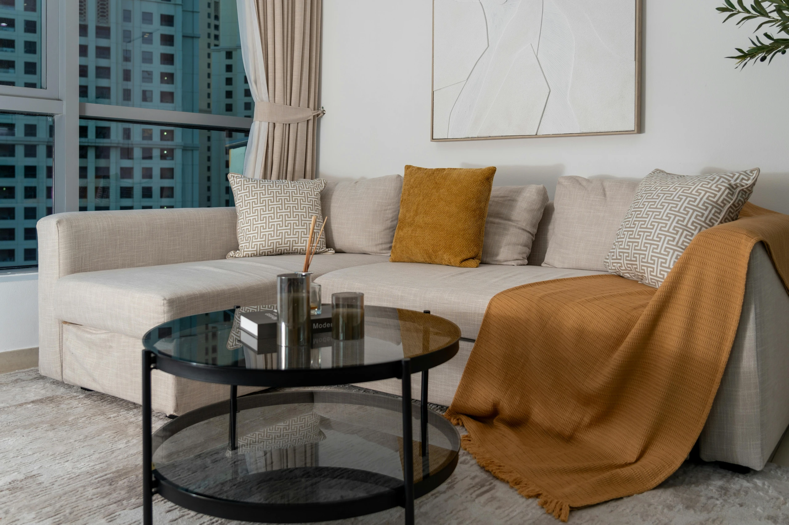 Modern living room setup showing how to decorate a round coffee table with incense sticks for a cozy and aromatic ambiance. The sleek black table features minimalist decor, including glass candle holders, a couple of stacked books, and a stylish incense diffuser, offering a versatile approach to contemporary table styling.