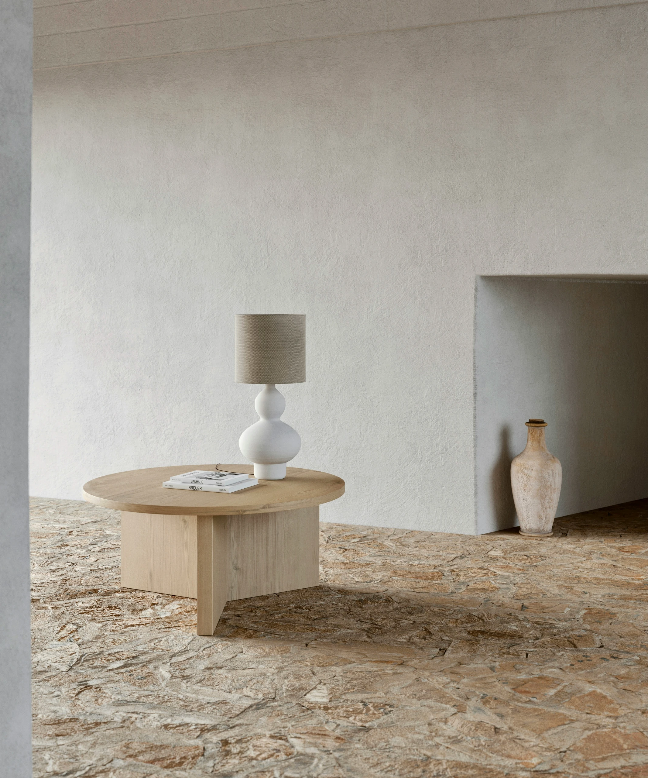 A serene example of how to decorate a round coffee table with a versatile, minimalist approach, featuring a light wood table styled with a bold statement lamp and a neatly stacked set of books, ideal for modern and Mediterranean-inspired interiors.