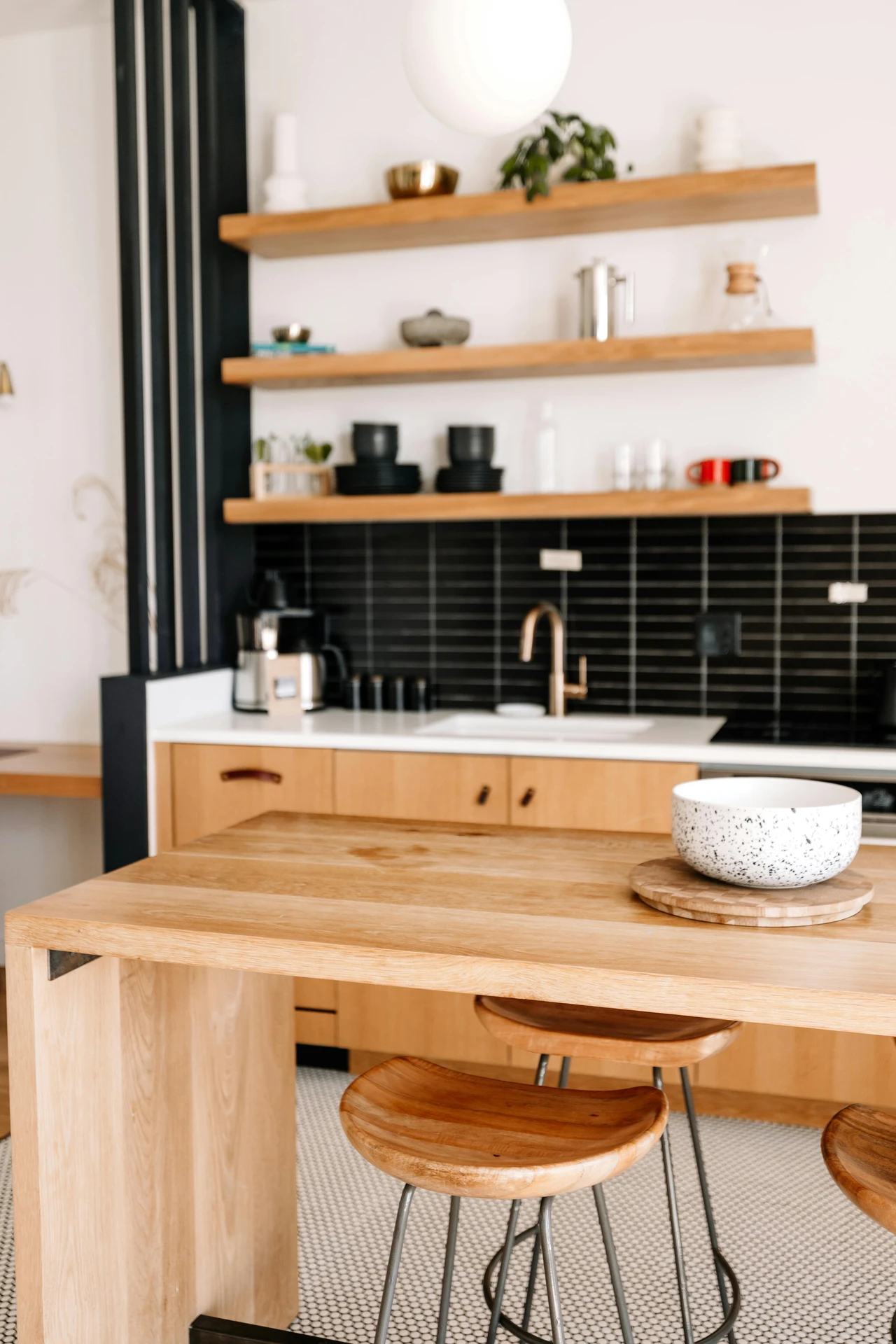 Bright and inviting kitchen featuring a wooden scandinavian kitchen island with matching wooden stools and a speckled ceramic bowl as a simple centerpiece. This setup highlights clean lines, open shelving, and natural materials, offering stylish kitchen island decor ideas for a minimalist and functional Scandinavian-inspired space.