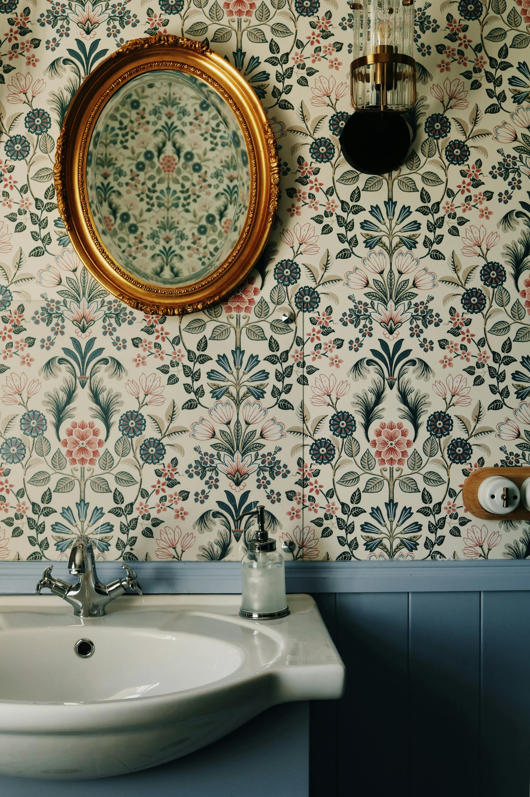 Charming small bathroom showcasing budget-friendly design with elegant patterned wallpaper, a classic white sink, and a vintage-style gold mirror. Perfect inspiration for small bathroom ideas on a budget.