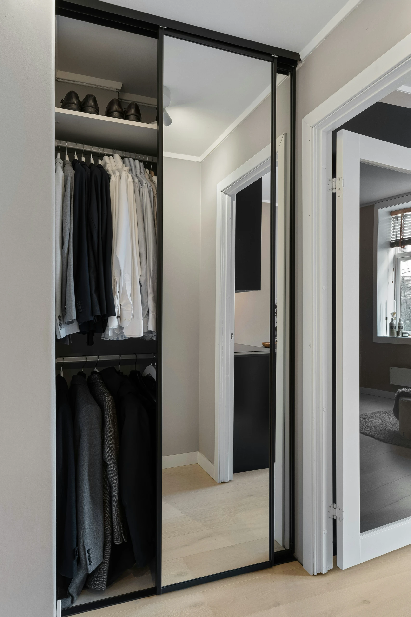 Modern small bedroom closet with sliding mirrored doors showcasing neatly organized clothing. An excellent example of small bedroom ideas with storage using sleek sliding closet doors to save space and enhance functionality.