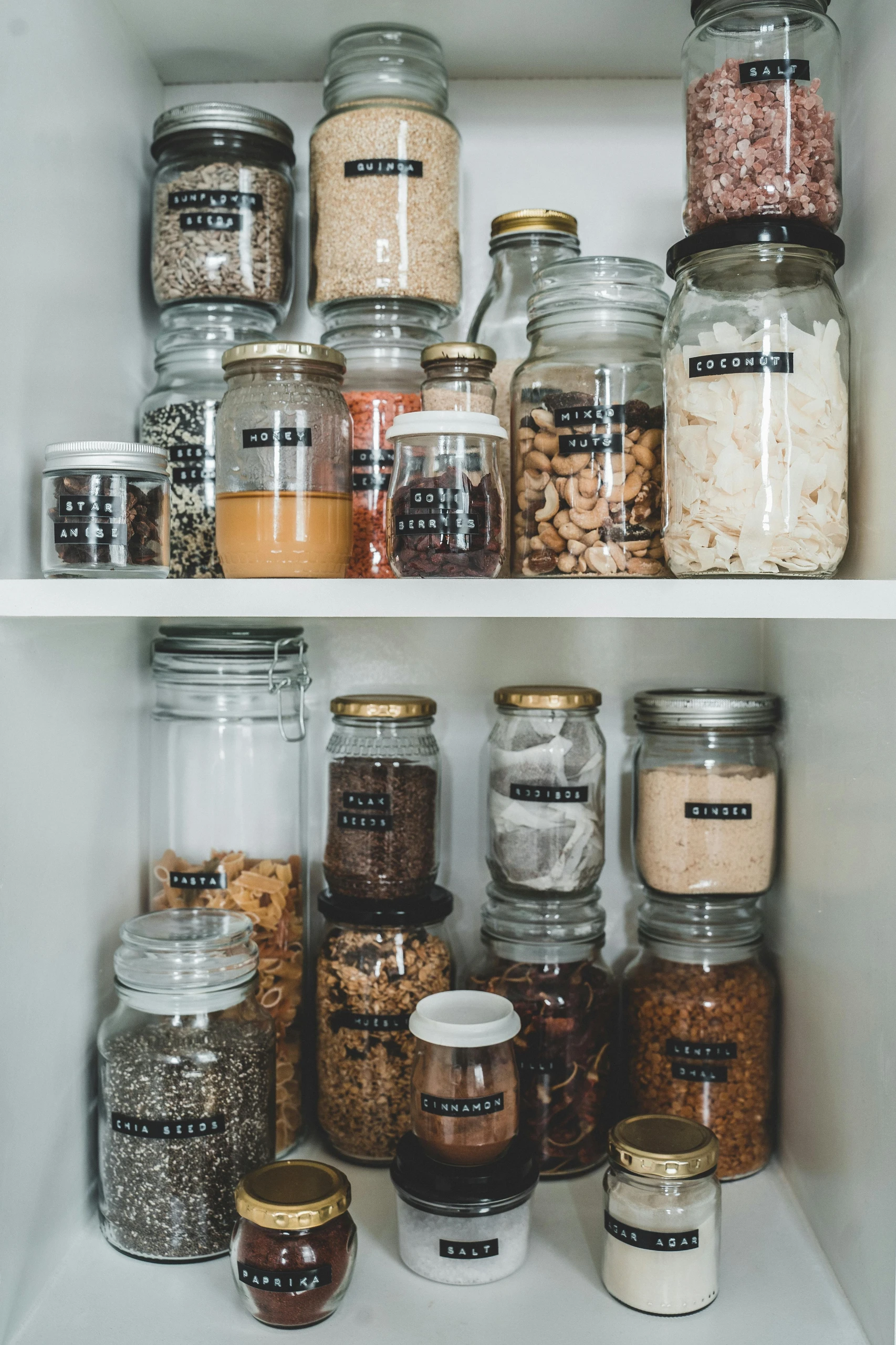 Organized pantry shelf showcasing labeled glass jars and containers filled with spices, grains, and snacks. A perfect example of small kitchen decor ideas that combine style and functionality.