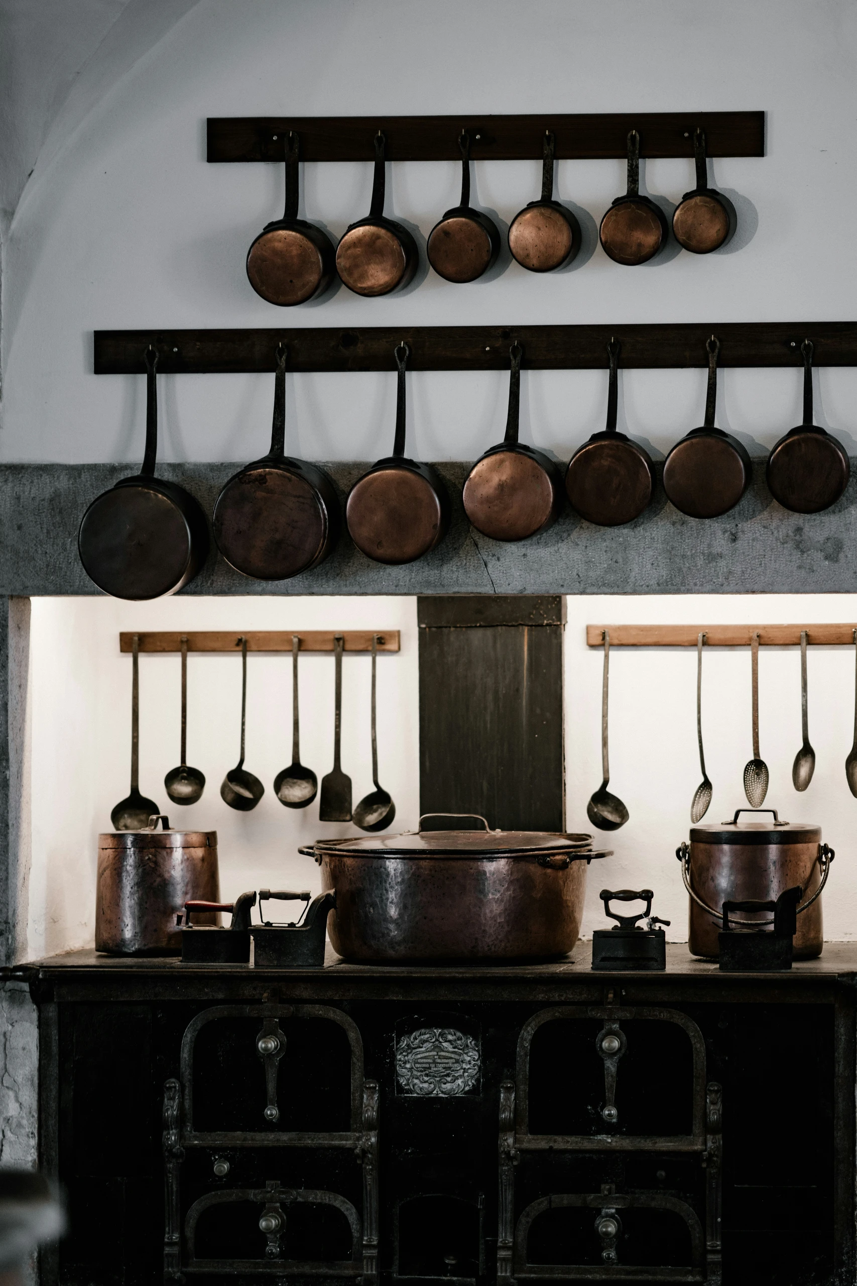 A charming kitchen space that blends modern and traditional elements, featuring antique black iron cookware and copper pans neatly hung on wooden racks. An inspiring example of small kitchen decor ideas with timeless character.