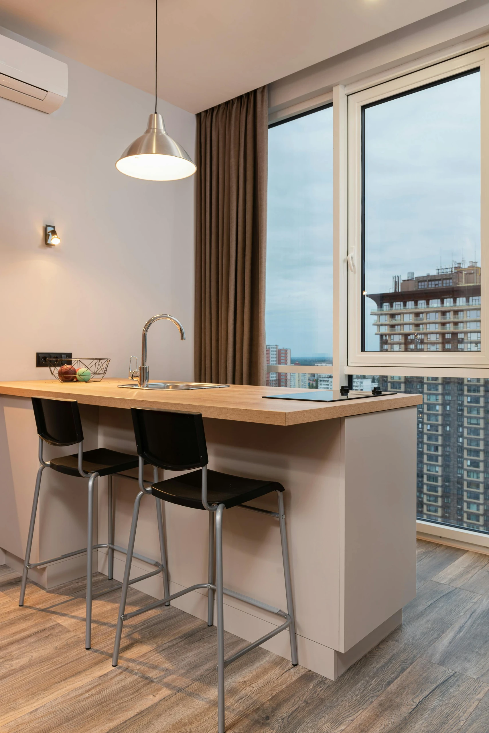 Modern high-rise kitchen featuring a sleek island with built-in sink and cooktop, perfect for small kitchen decor ideas that emphasize multifunctional furniture with seating, prep space, and storage in one.