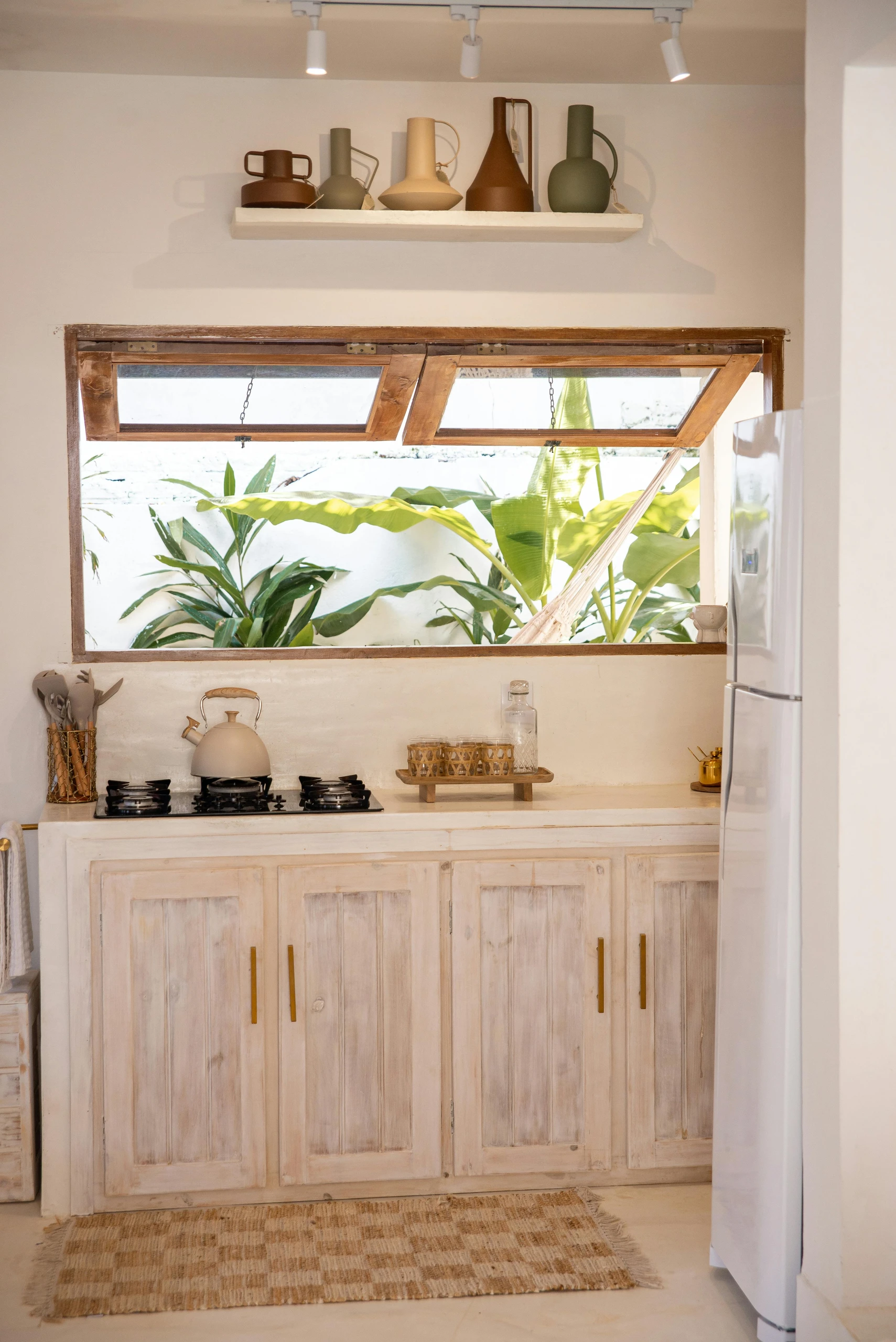 Bright and airy kitchen showcasing small kitchen decor ideas that embrace natural light, featuring rustic wooden cabinets, earthy tones, and a large window with lush green outdoor views.