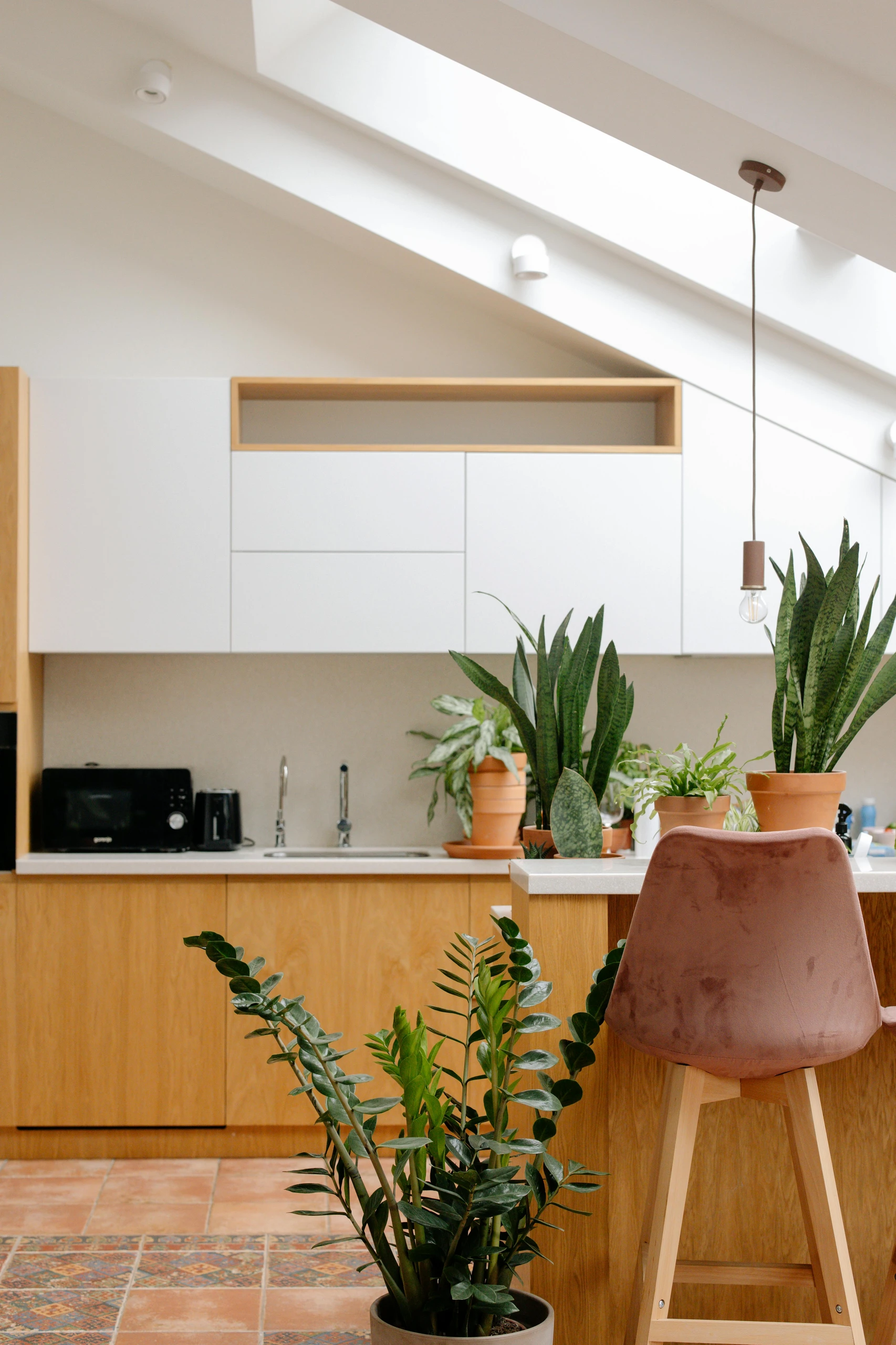 Bright and modern kitchen filled with small kitchen decor ideas that highlight the use of plants and greenery to bring life and freshness into the space, featuring terracotta pots and a cozy natural aesthetic.