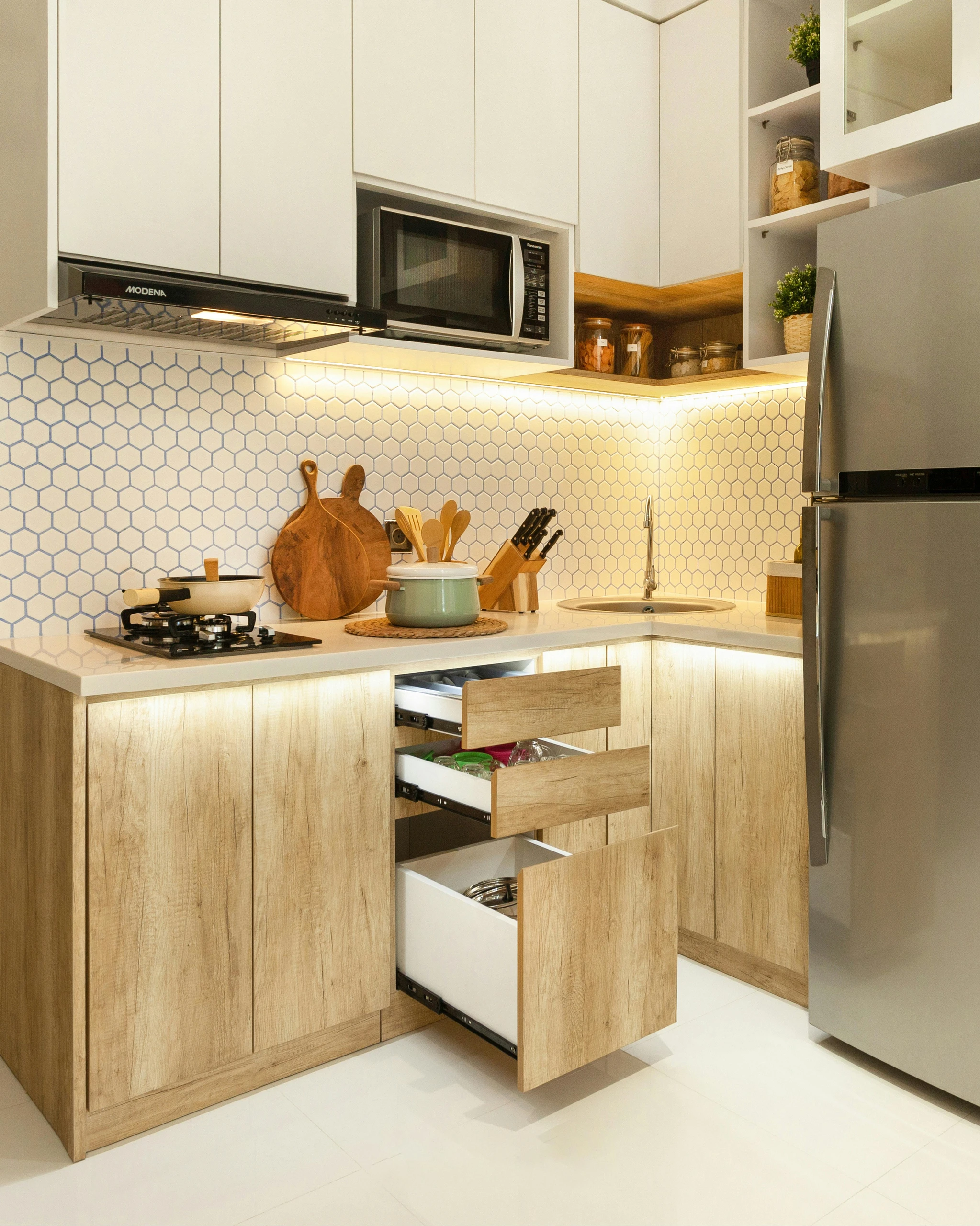Modern compact kitchen showcasing small kitchen decor ideas with smart storage solutions, featuring pull-out drawers, wood-accented cabinets, and under-cabinet lighting for a clean and functional look.