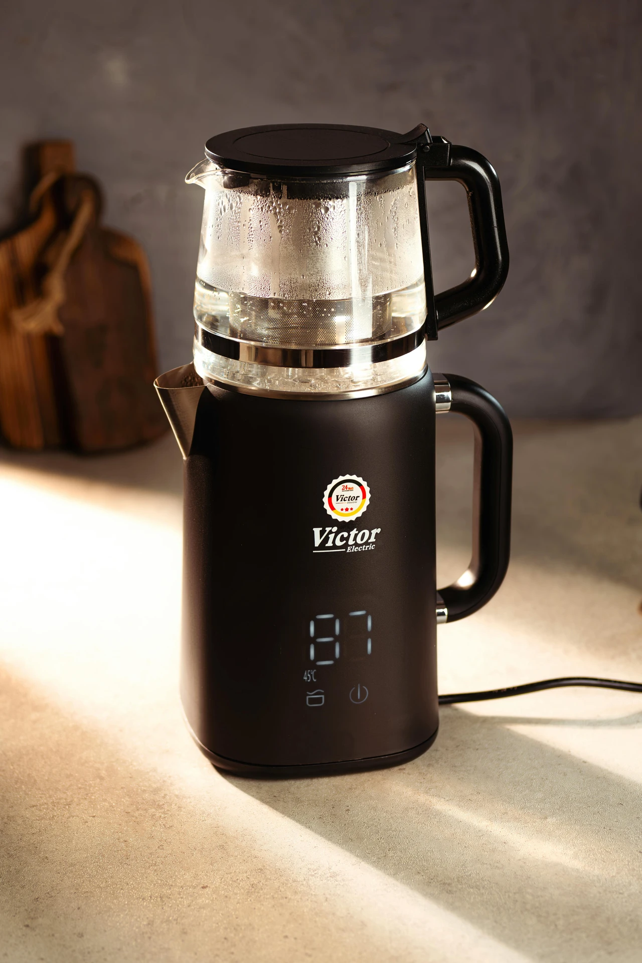 Sleek black electric kettle with a transparent glass pot and built-in tea infuser, showcased as part of versatile small kitchen appliances. The kettle features a digital temperature display reading 87°C, ideal for brewing tea, coffee, or preparing hot water for various recipes, blending modern design with practical functionality for everyday use.