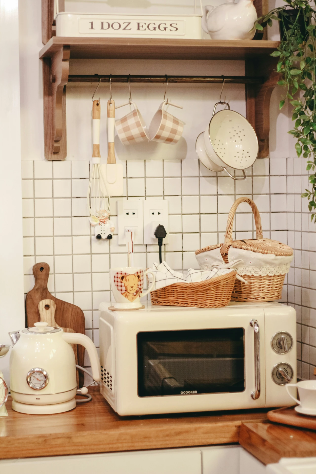 A cozy kitchen counter featuring small kitchen appliances, including a retro-style microwave and an electric kettle, surrounded by wicker baskets, wooden cutting boards, and ceramic mugs. The setup blends functionality and charm, showing how a microwave can be part of both quick meal prep and a warm, inviting kitchen atmosphere.