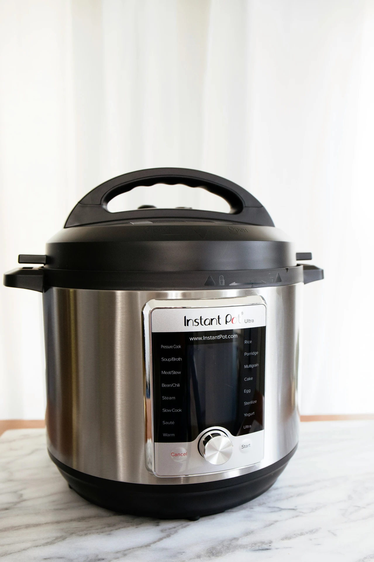 A sleek stainless steel multi cooker, part of the essential small kitchen appliances collection, displayed on a marble countertop. This versatile appliance offers multiple cooking modes, from pressure cooking and slow cooking to steaming, sautéing, and making yogurt, making it ideal for preparing a wide variety of meals with ease.
