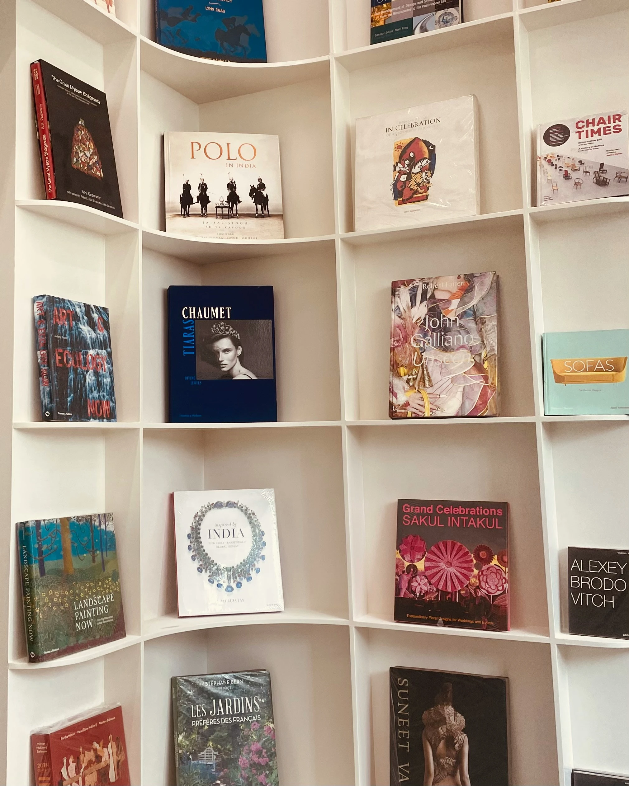 Creative bookshelf decorating ideas for showcasing special books in a striking, curved wall-mounted shelf. Each cubby highlights a single large-format book with colorful covers on topics like art, design, fashion, and travel, turning the shelf into a versatile gallery-style display. Ideal for collectors or anyone wanting to spotlight visually impactful books in a modern and organized way.