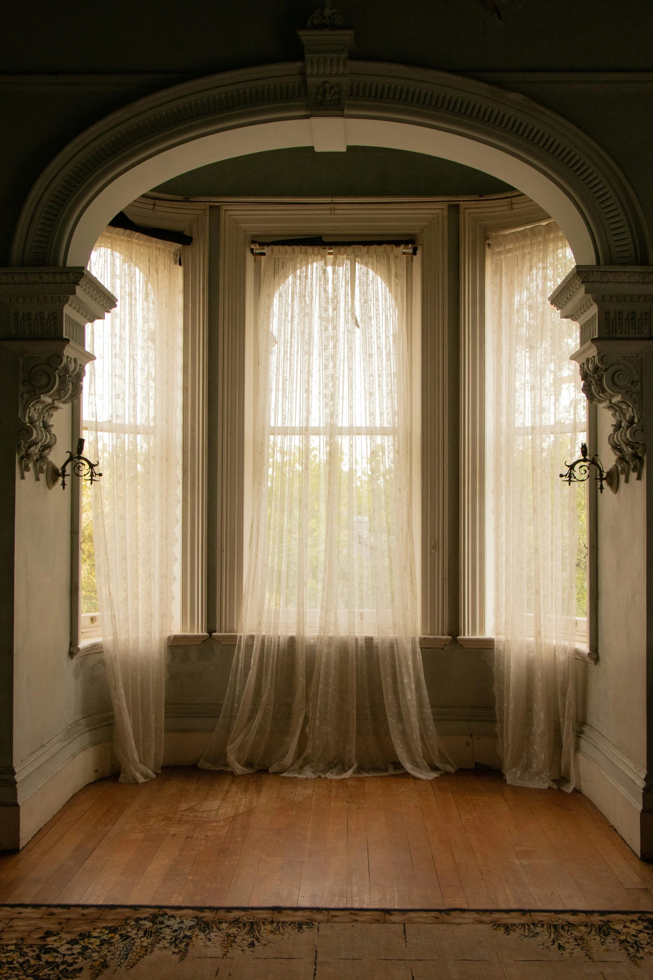 Elegant curtain ideas for the living room showcasing tall windows draped with delicate sheer fabric in a soft lace pattern. The light-filtering design adds a timeless, romantic touch while allowing natural sunlight to brighten the room, making it a versatile choice for both classic and modern interiors.