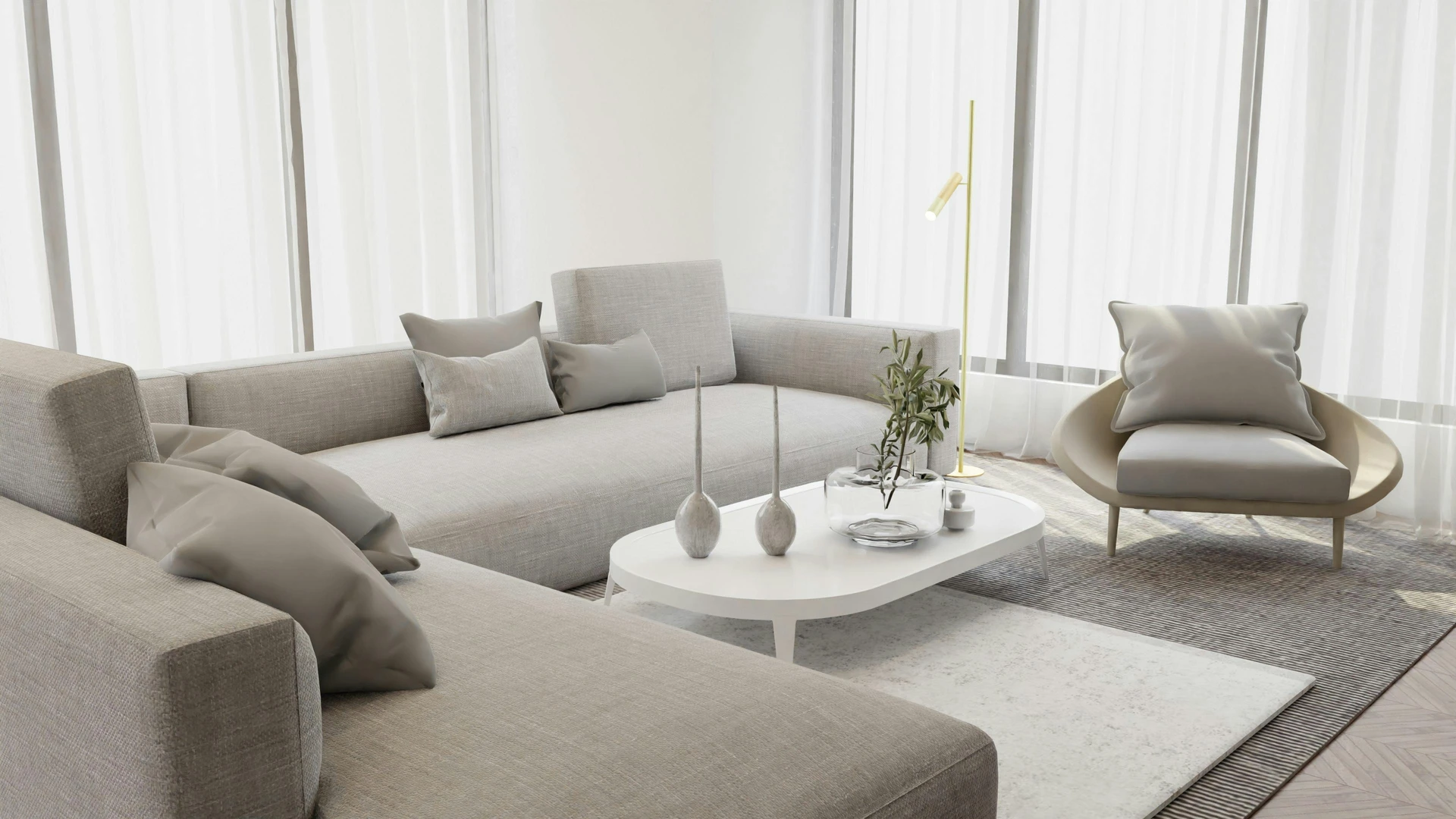 Bright and airy living room with a spacious grey sofa styled in a tone-in-tone palette, paired with matching grey cushions, a light armchair, and a white modern coffee table. Sheer curtains allow soft natural light to fill the room, while minimal decor like slim vases and a small plant keep the design calm and cohesive. The setup highlights how to style a grey sofa using layered neutral shades to create an elegant, harmonious atmosphere.