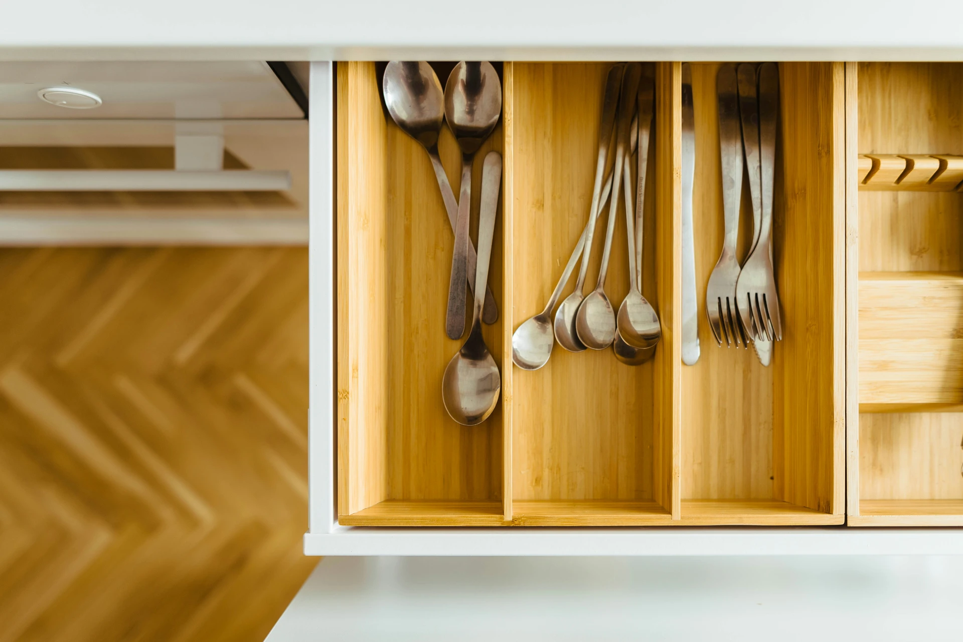 Neatly arranged cutlery in a wooden organizer with multiple drawer dividers, keeping spoons, forks, and other utensils separated for easy access. This smart storage method is a perfect example of kitchen organization ideas for small kitchens, helping to maximize drawer space, reduce clutter, and maintain a clean, functional cooking area.