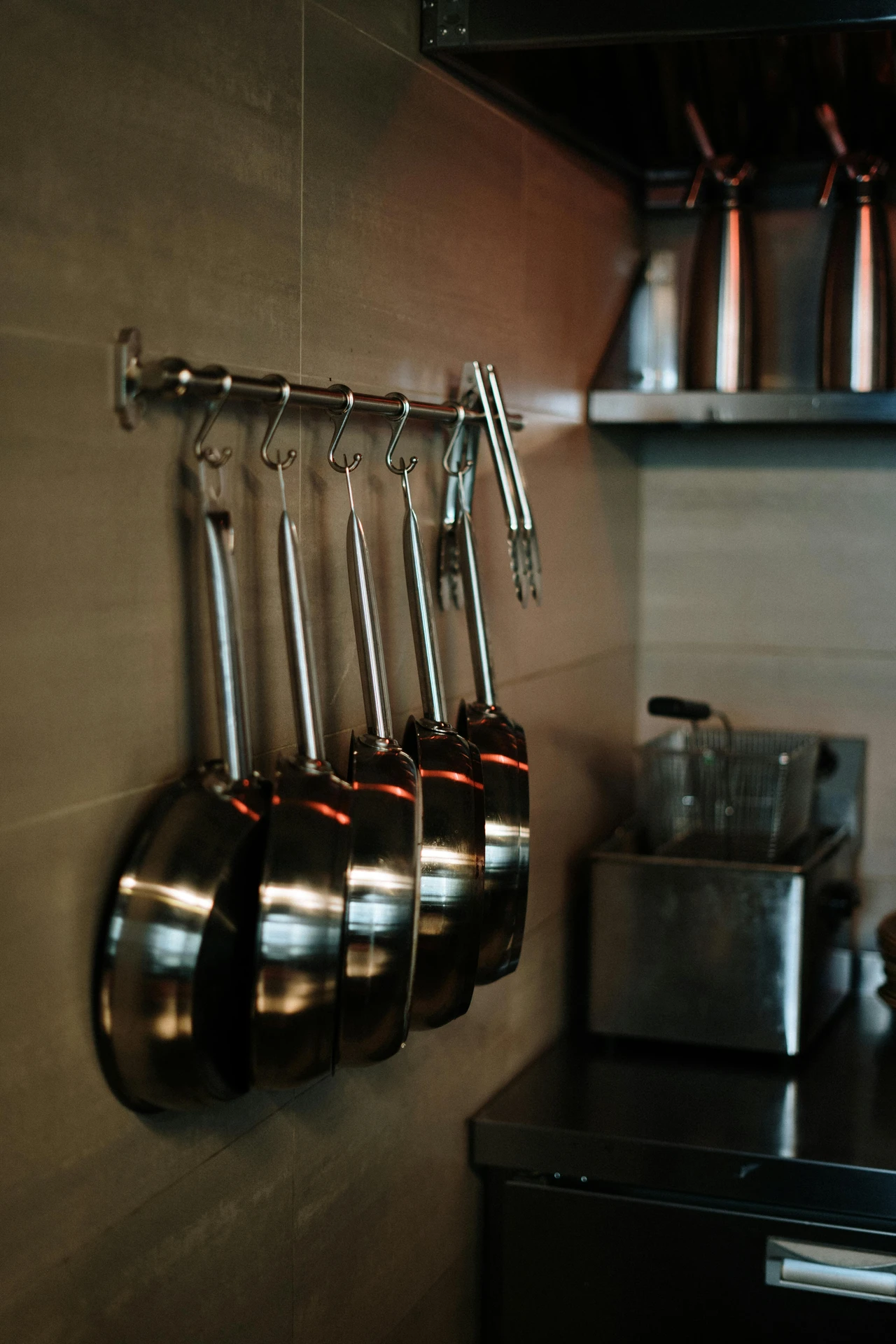 A sleek metal rod with hooks used for hanging pots and pans in a compact kitchen, showcasing smart kitchen organization ideas for small kitchens. This space-saving setup keeps cookware easily accessible while freeing up cabinet space, making it a versatile solution for both home and professional kitchens.