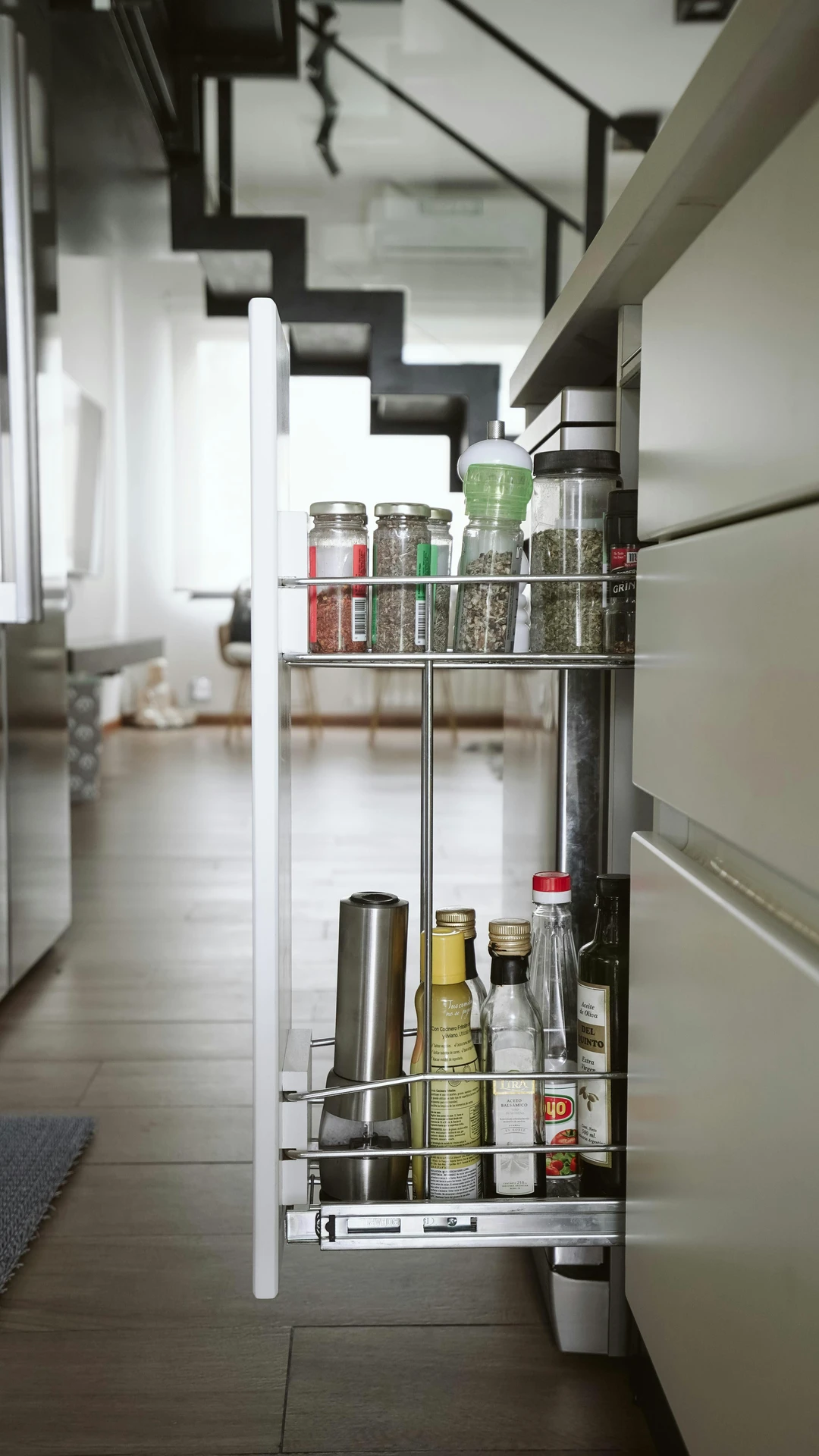 A modern kitchen featuring sleek pull-out-cabinets, neatly storing spices, oils, and condiments in a narrow vertical space. The compact design maximizes storage efficiency, making it a smart example of kitchen organization ideas for small kitchens. The pull-out shelf blends seamlessly with the cabinetry, offering both functionality and a clean, minimalist look suitable for various kitchen styles.