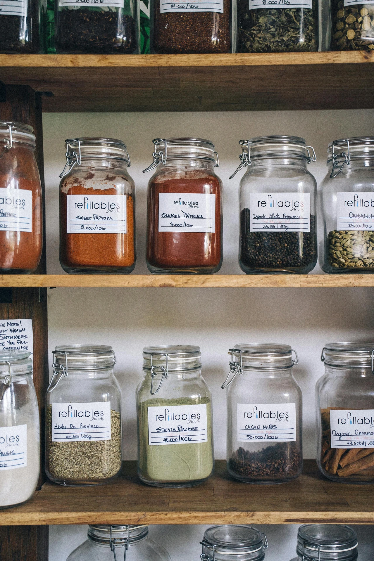 Glass jars filled with various spices and labeled neatly, displayed on wooden shelves, illustrating how to organize your spices in a rack as part of practical kitchen organization ideas for small kitchens. The setup offers a versatile and stylish way to keep seasonings accessible, reduce clutter, and enhance the overall kitchen aesthetic.