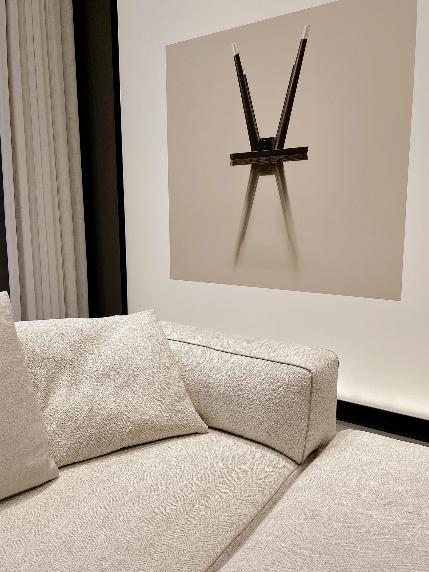 Contemporary living room makeover with a soft beige sofa and matching cushions placed against a minimal wall. A striking abstract piece of wall art hangs above, proving how easily you can integrate wall art to elevate a neutral seating area. Floor-to-ceiling curtains add warmth and texture, balancing the clean, modern design.