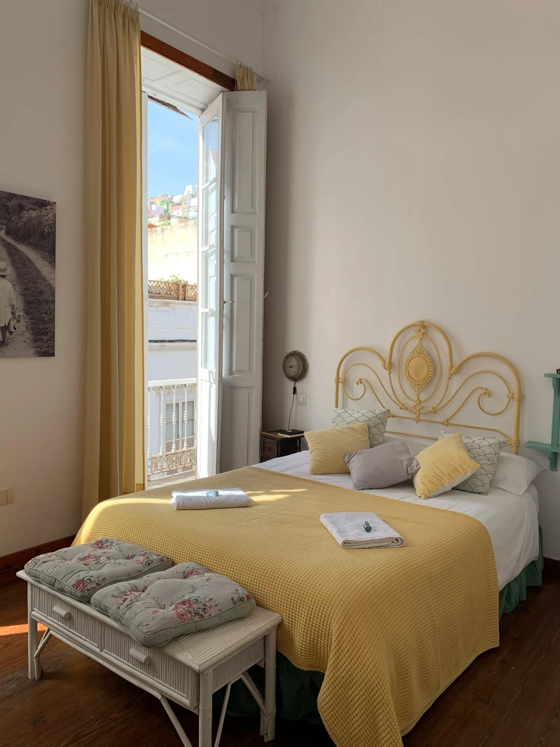 Close-up of a cozy bedroom featuring a padded bench with a wooden shelf at the foot of the bed, showcasing multi-functional furniture as part of small bedroom ideas with storage.