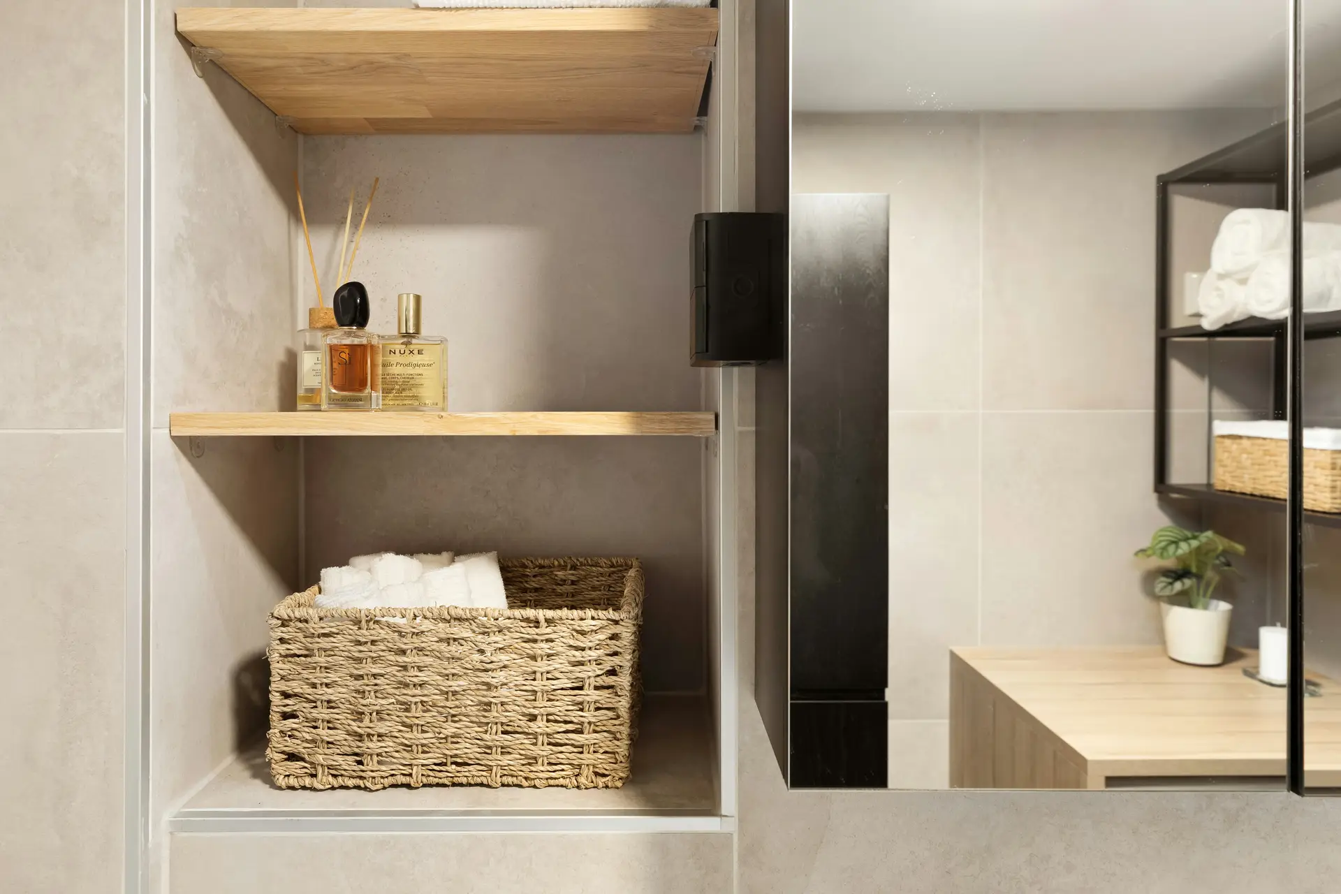 Thoughtful small bathroom remodel showcasing smart storage with wood accents and natural textures. The choice to install floating shelves creates space for rolled towels, woven baskets, and decorative items, adding both function and warmth to a compact, modern bathroom design.