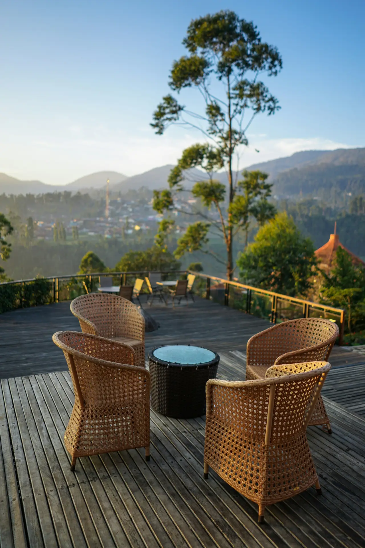 Peaceful outdoor deck surrounded by lush greenery and mountain views, featuring wicker chairs with a small round table in the center. The cozy setup creates a relaxing spot to enjoy nature and sunset views, ideal for those seeking patio decor ideas that blend comfort, warmth, and scenic beauty.