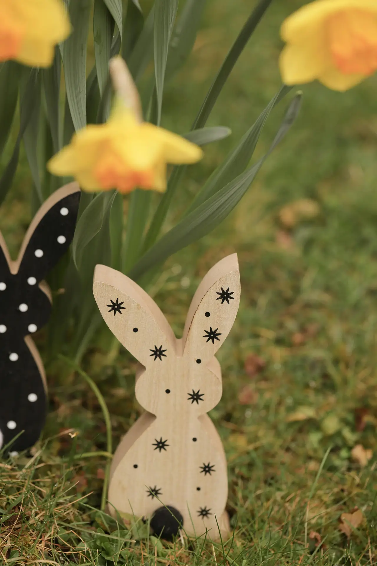Spring decor ideas featuring outdoor spring decor with small wooden bunny figures placed on grass beneath blooming yellow flowers, creating a playful seasonal accent that works well in gardens, patios, or front yard displays.