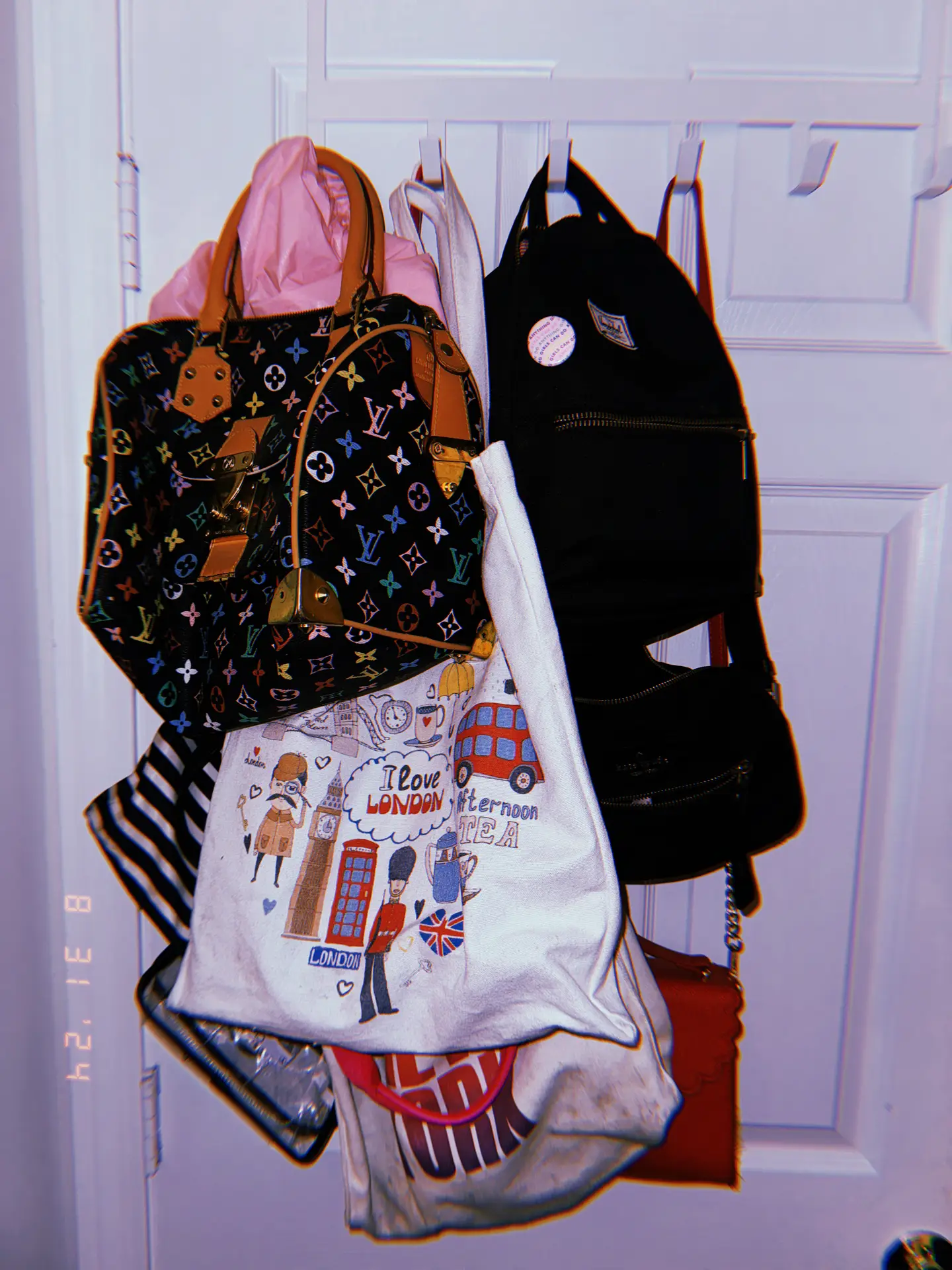 An over-the-door rack mounted on a white door holds multiple handbags, backpacks, and tote bags layered on hooks, showcasing organization ideas for small spaces by using over-the-door racks to keep everyday accessories accessible without taking up floor or closet space.