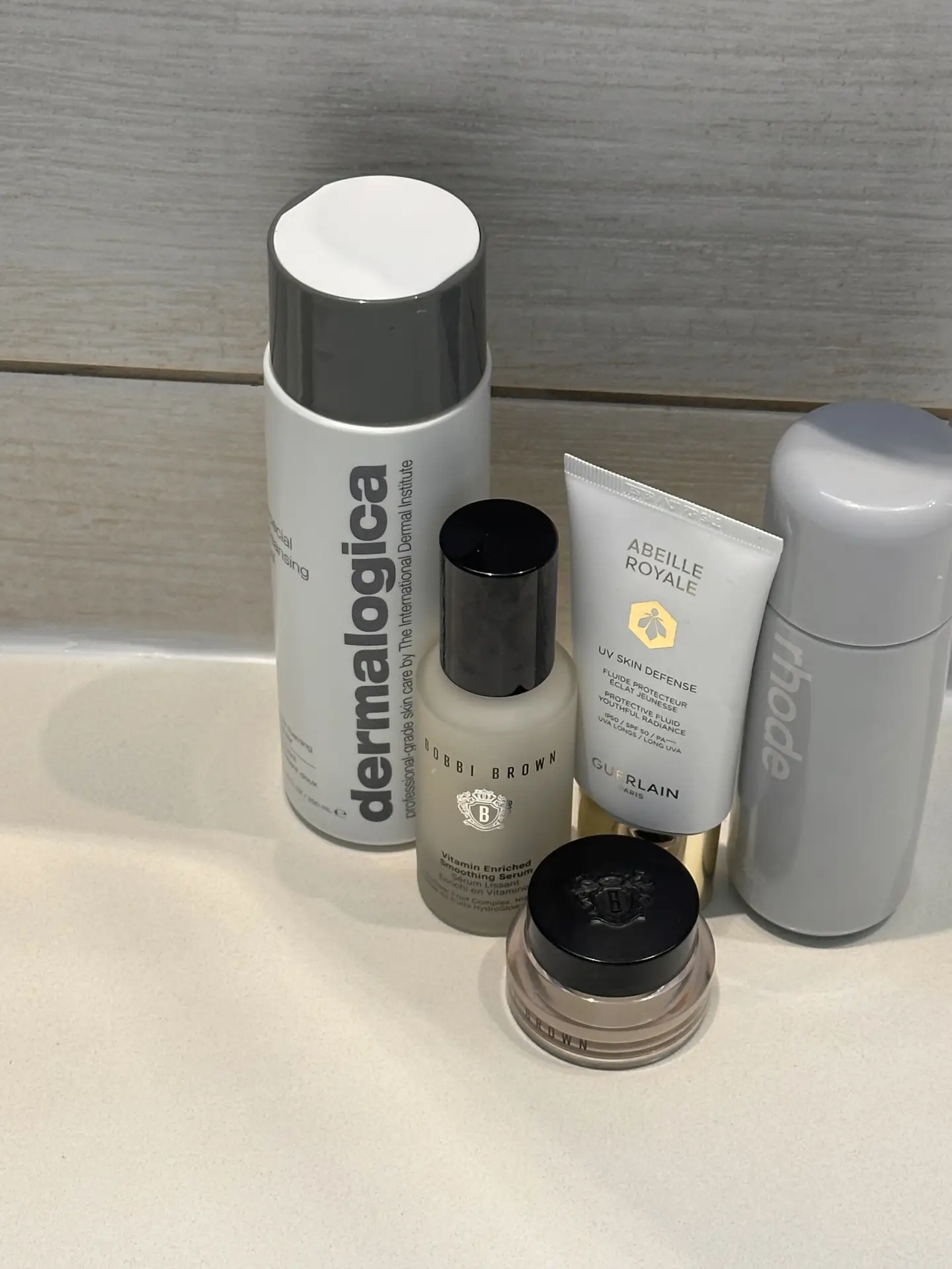 A selection of skincare and cosmetic products neatly arranged on a bathroom counter, showing items like cleansing spray, serum, sunscreen, and cream as part of a spring cleaning checklist with a cosmetics check to review, organize, and refresh daily beauty essentials.