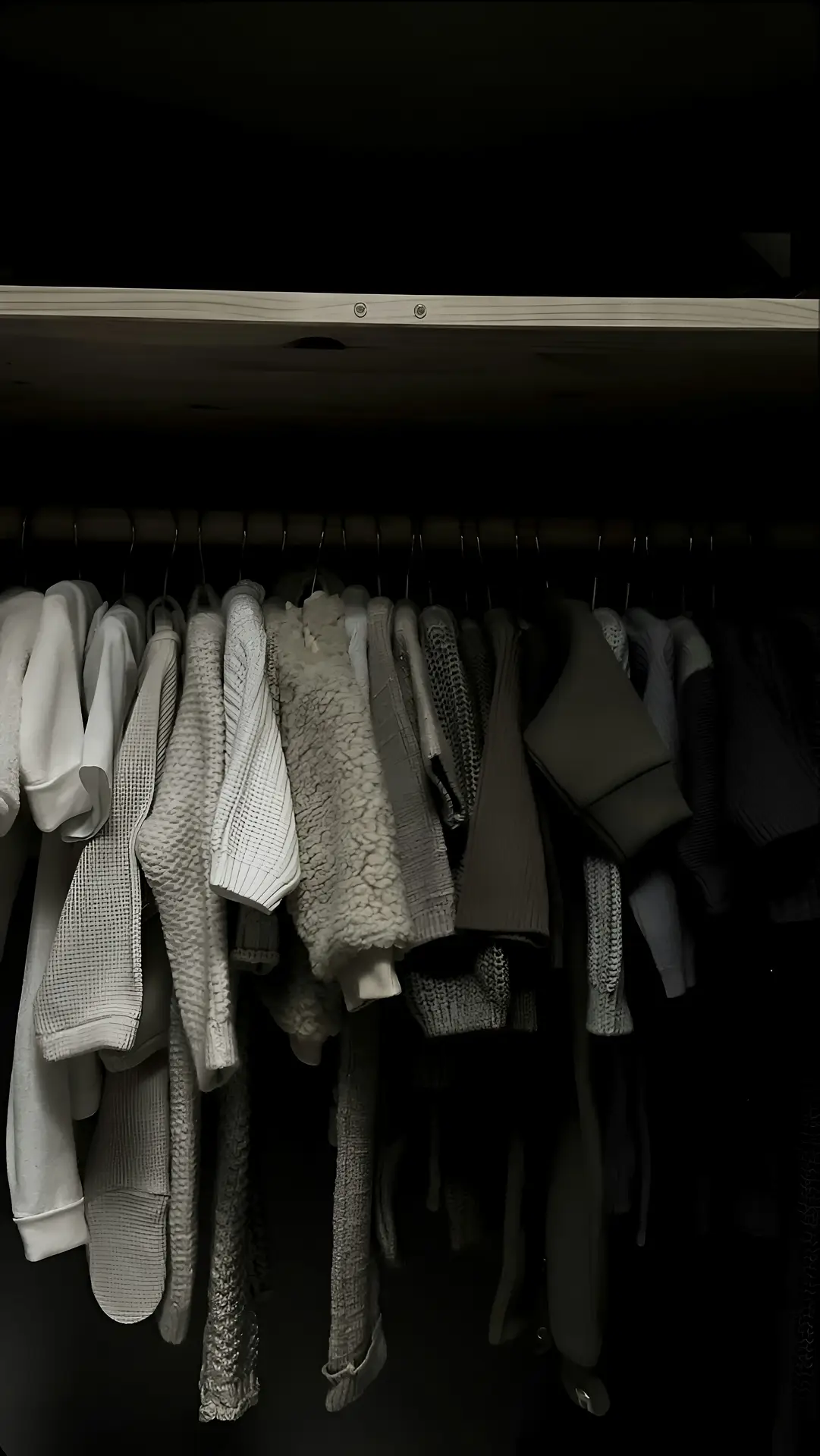 A wardrobe rail filled with neatly hung sweaters, coats, and knitwear in neutral tones, suggesting a spring cleaning checklist step focused on storing winter clothes, organizing seasonal layers, and creating more space in the closet.