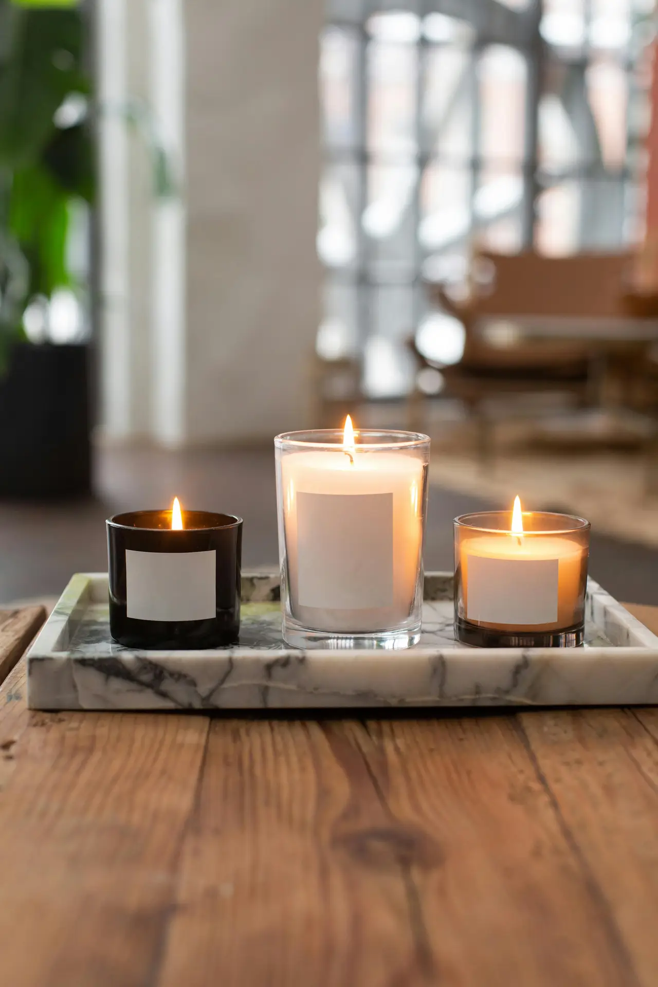 Elegant spring decor ideas for living room featuring spring candles arranged on a marble tray, with softly glowing flames in glass holders placed on a wooden coffee table, adding warmth and a calm seasonal mood to a bright, modern interior.