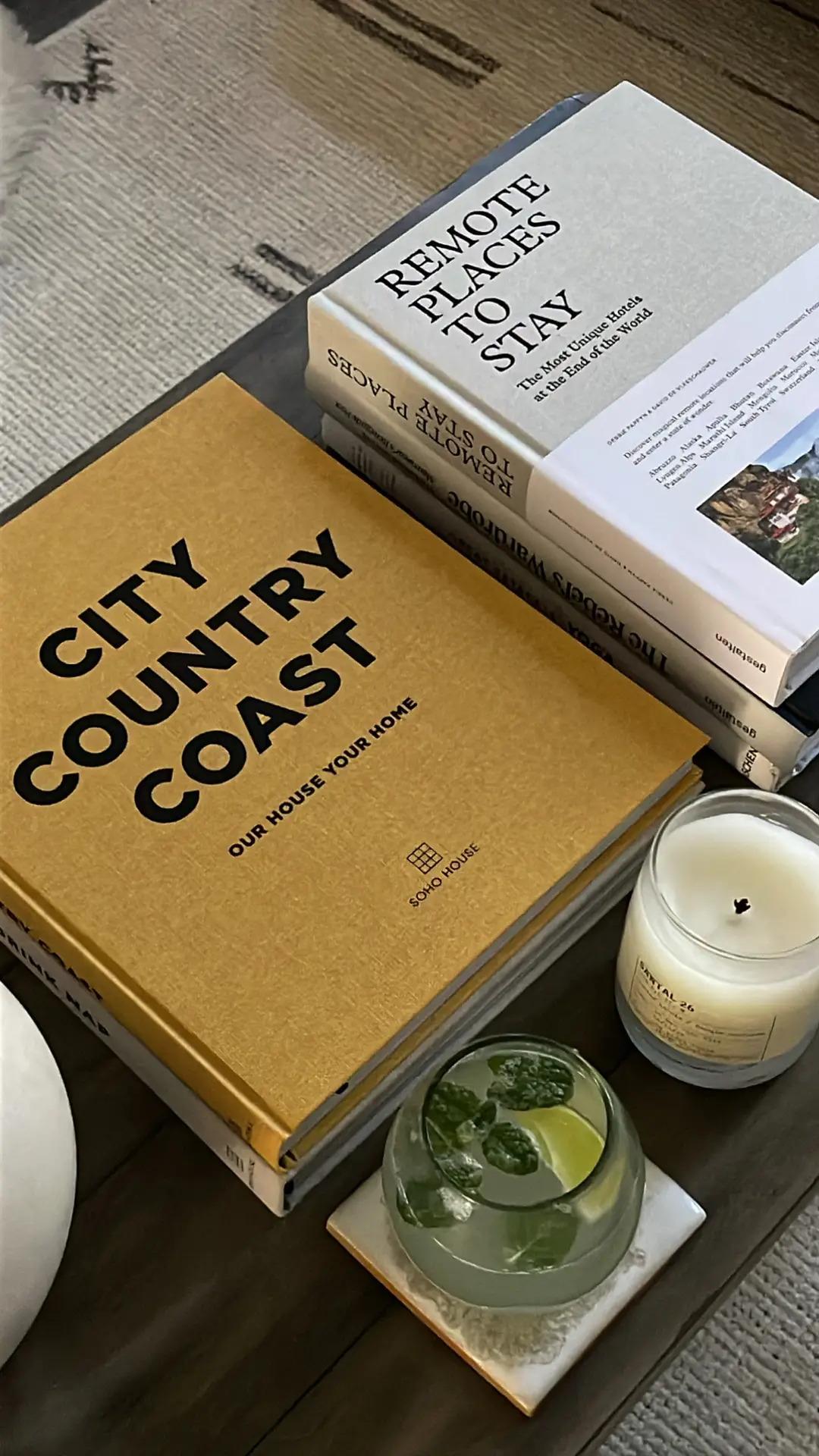 A curated and cozy arrangement showcasing relaxed summer decor ideas. Two large summer coffee table books, one with a mustard yellow cover titled 