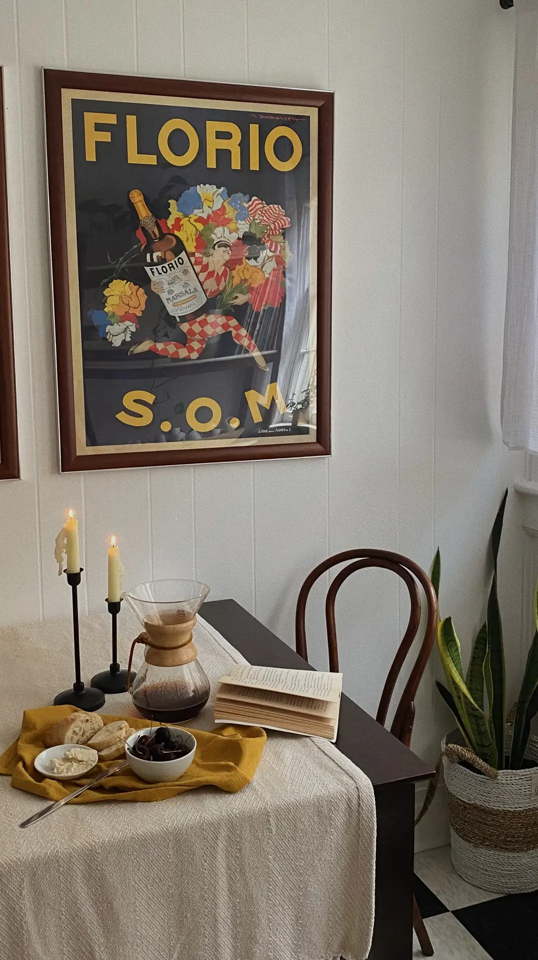 A cozy breakfast corner filled with nostalgic summer decor ideas. Hanging on the white paneled wall is a large, vintage-style summer print for 