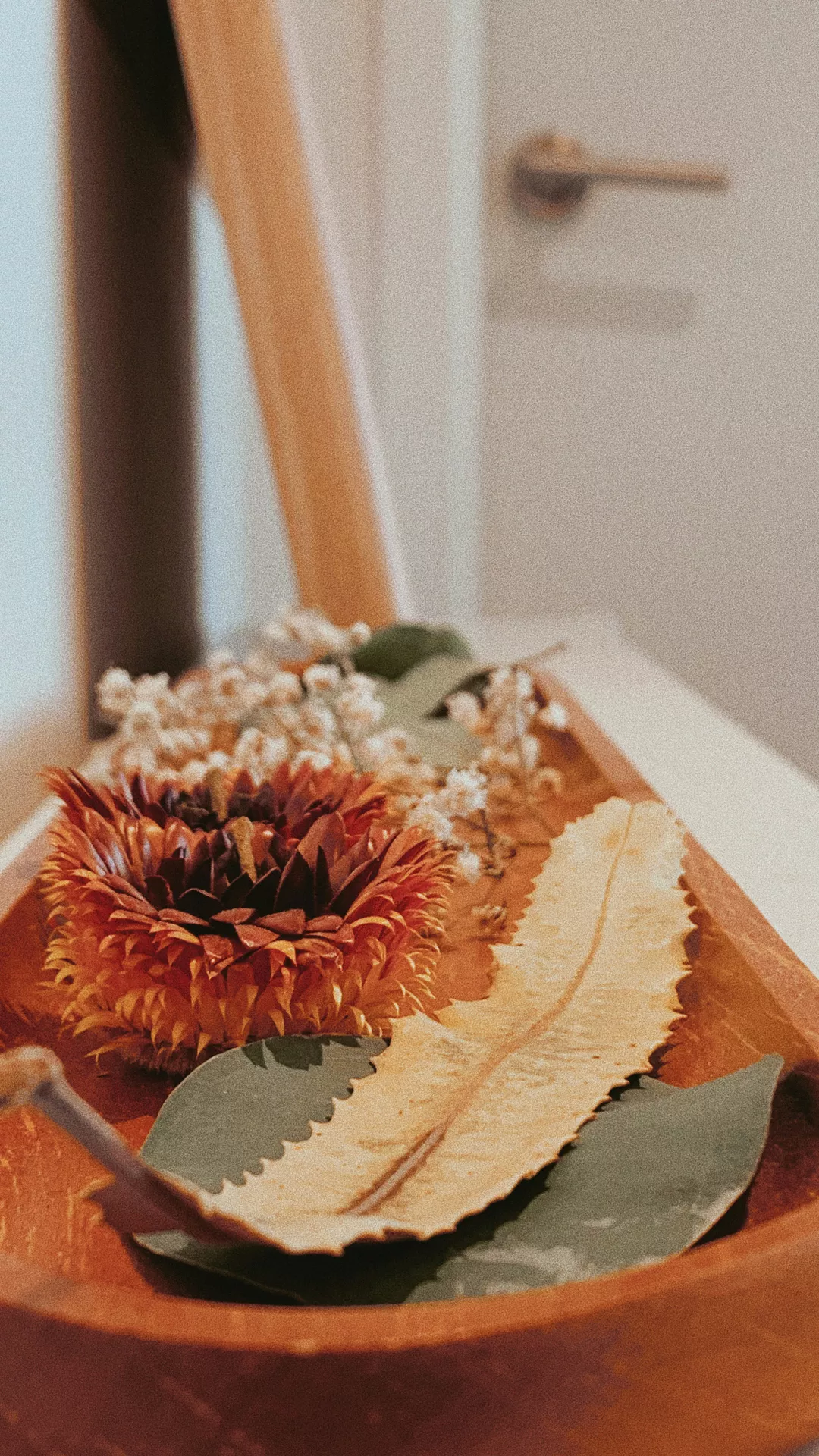Fall tray decor ideas featuring Dried Fall Flowers arranged in a rustic wooden tray with preserved autumn blooms, dried leaves, delicate white florals, and eucalyptus stems, creating a simple, warm, and nature-inspired seasonal accent.