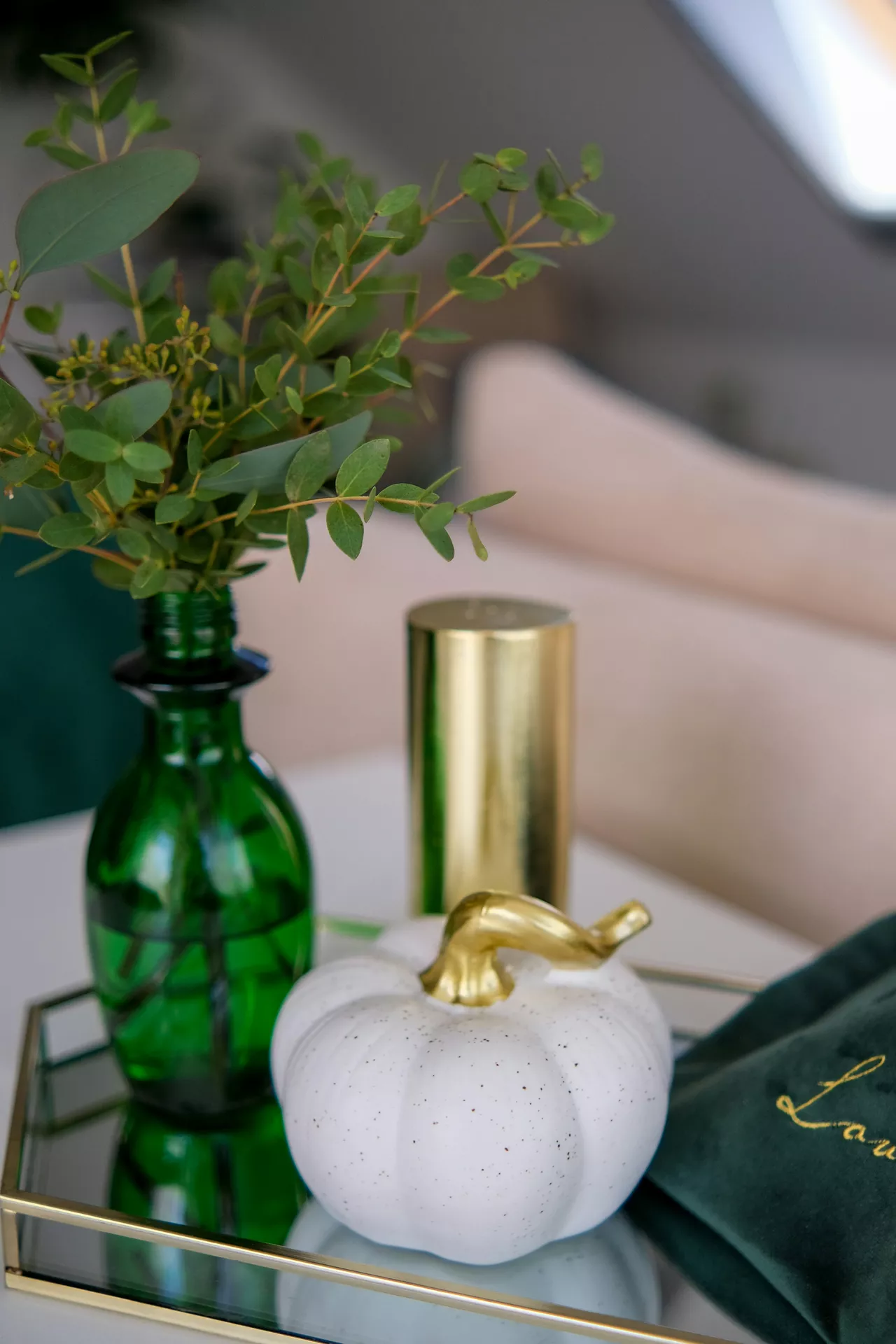 Fall tray decor ideas showcasing an Elegant Pumpkin With Gold Detail displayed on a mirrored tray alongside a green glass vase with fresh eucalyptus stems and a sleek gold candle holder, creating a modern and sophisticated autumn centerpiece.